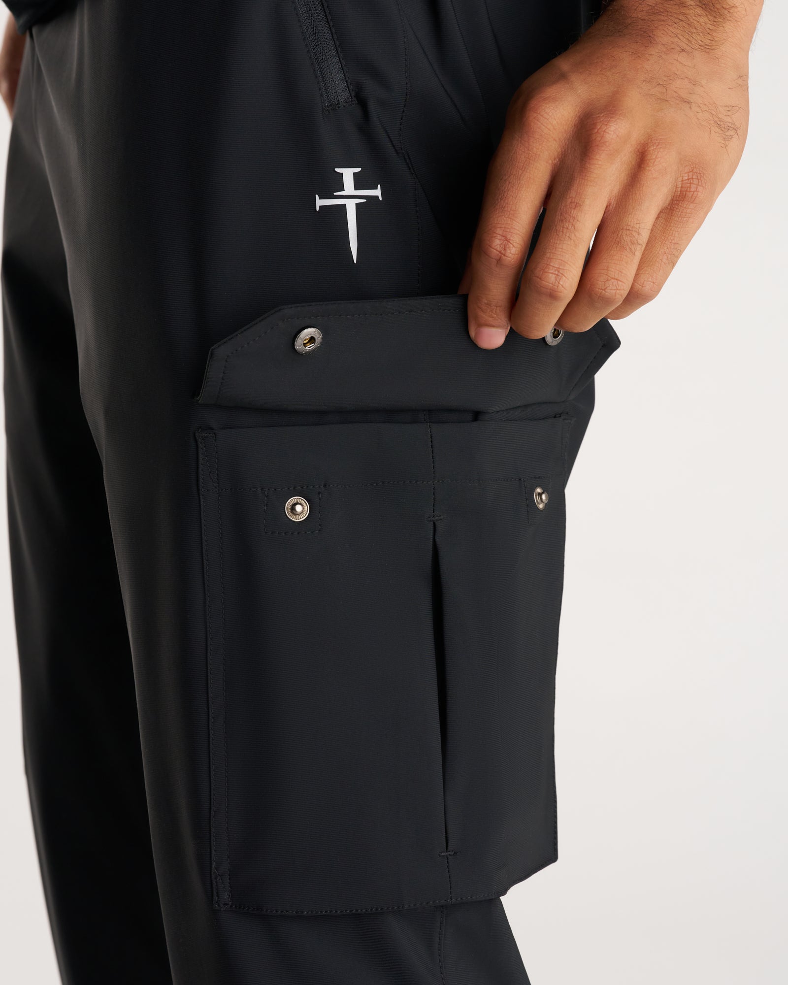 Close-up of black Vapor-Lite Cargo Jogger side cargo pocket with snap buttons and Three Nails logo embroidery.