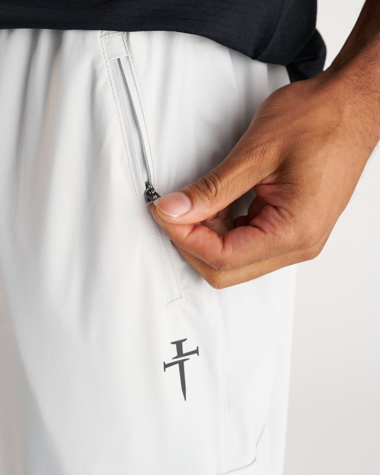 Close-up detail of Vapor-Lite Cargo Jogger in Stone showing zippered side pocket and brand logo.