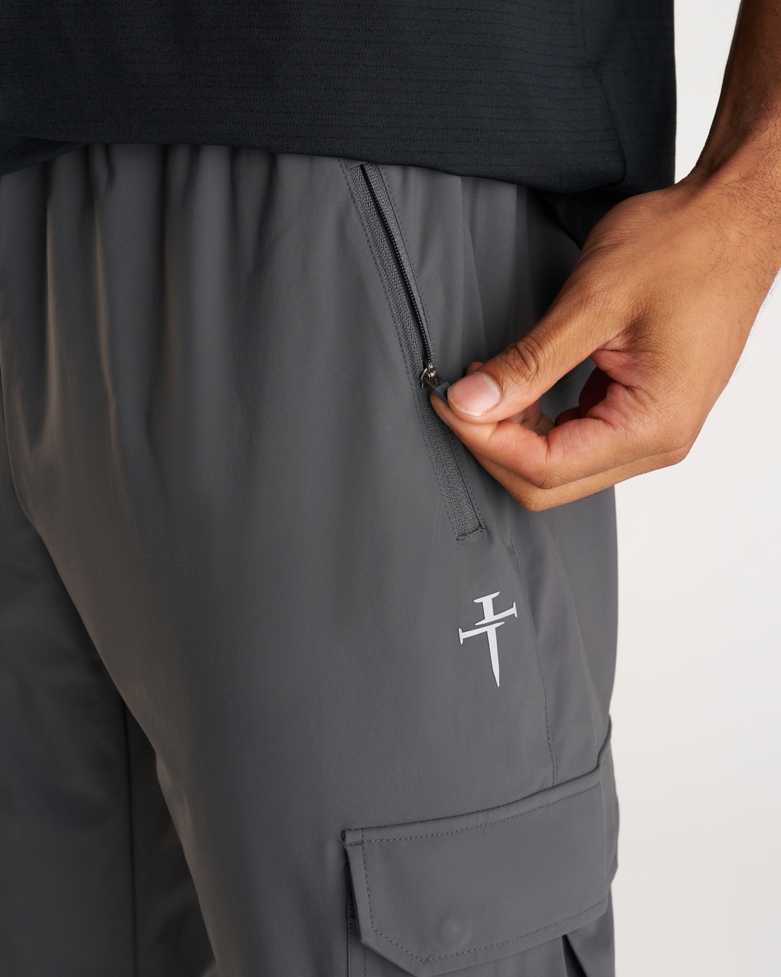 Close-up detail of Space Grey Vapor-Lite Cargo Jogger showing zippered side pocket and embroidered Three Nails logo.