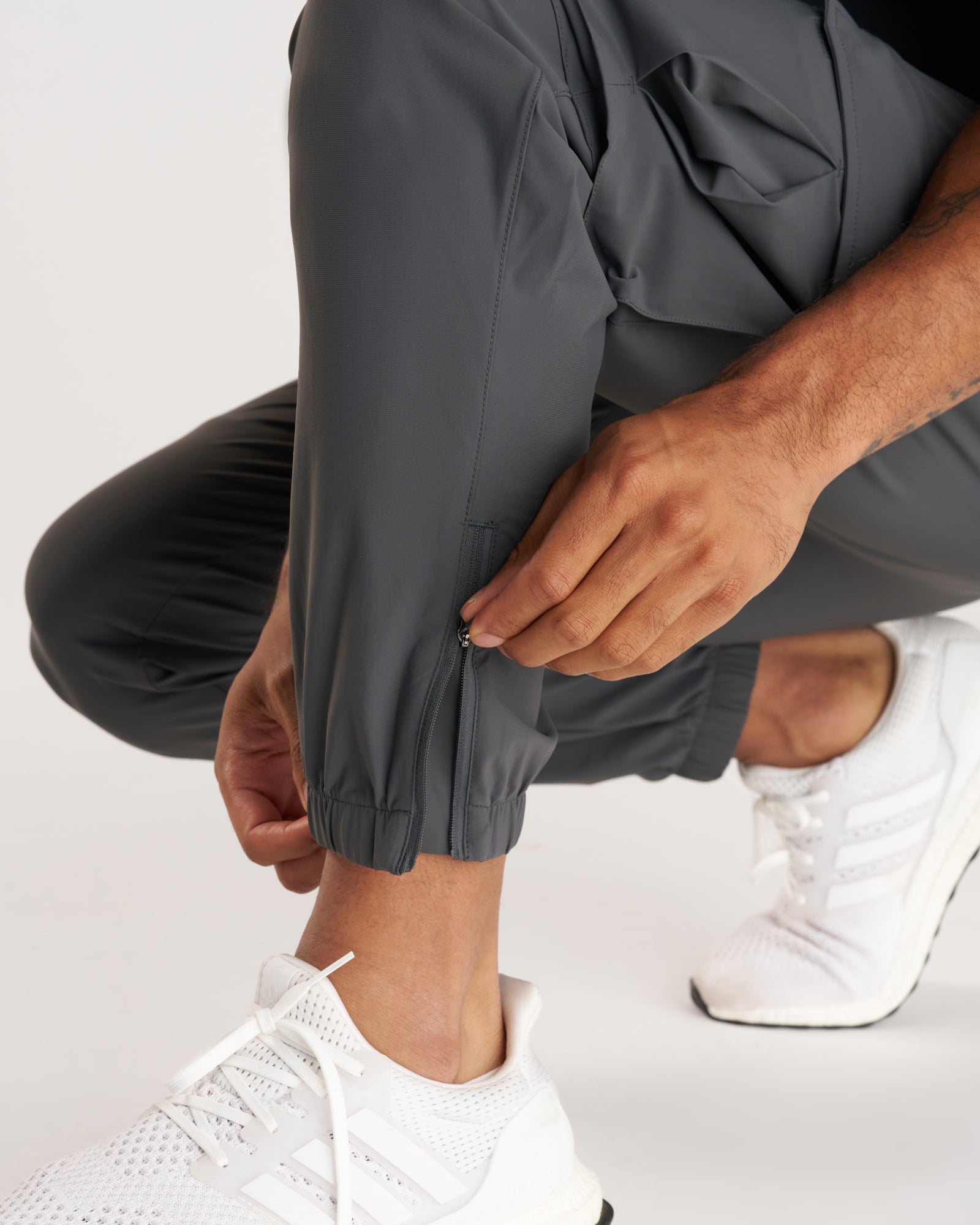 Close-up of Vapor-Lite Cargo Jogger in Space Grey showing ankle zip detail on a crouching model.