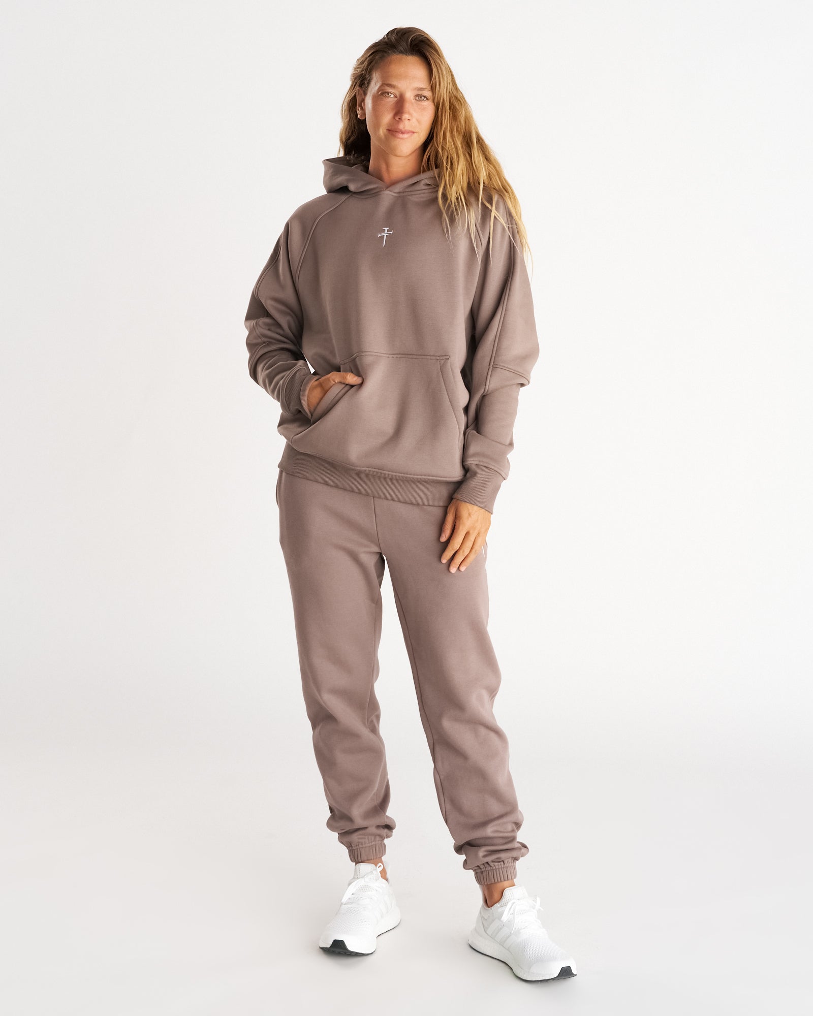 Woman wearing Signature Fleece Sweatpants in Deep Taupe, front view, paired with matching hoodie and white sneakers. #model_B