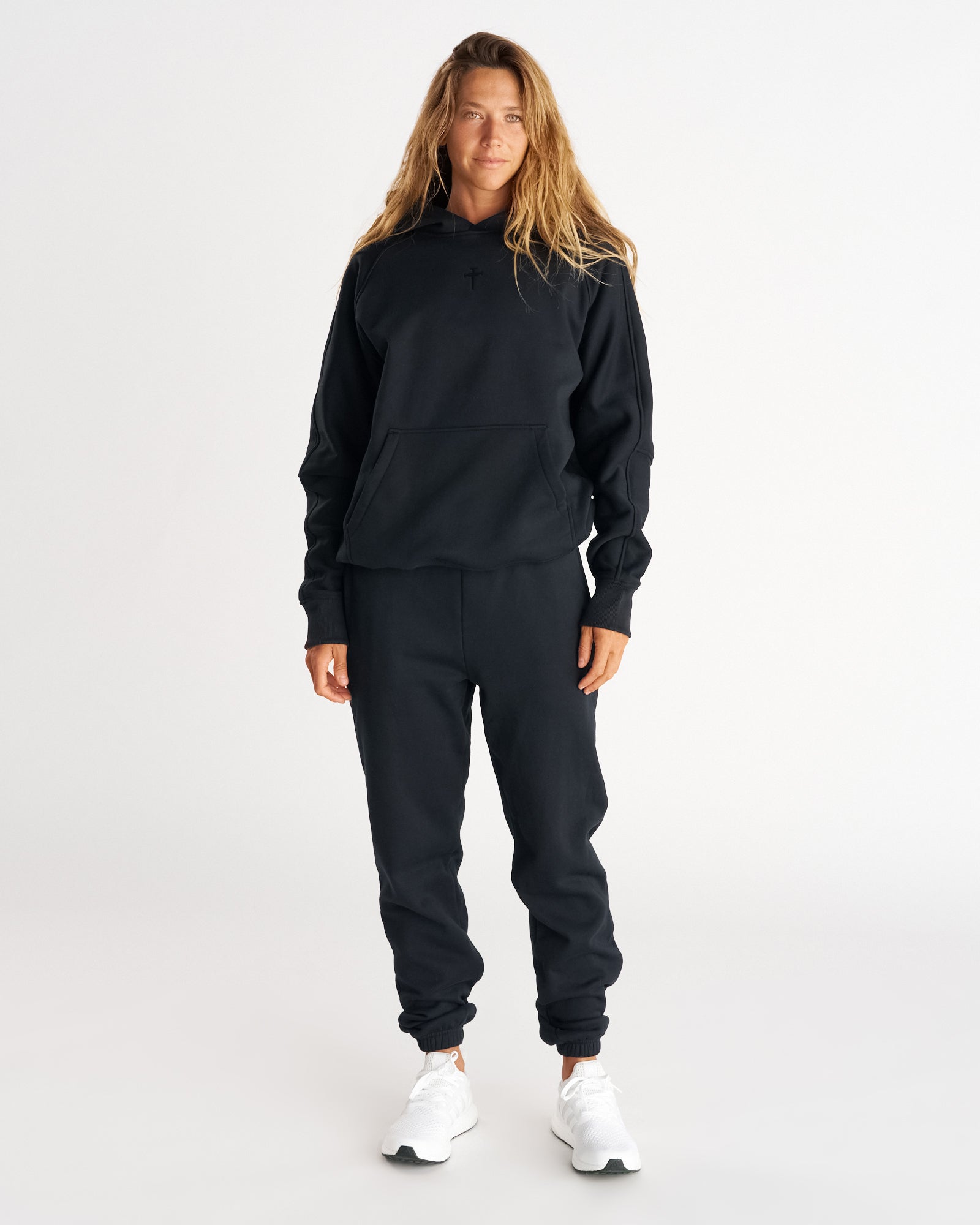 Front view of Signature Fleece Sweatpants in Blackout worn by a model with a matching black hoodie and white sneakers.