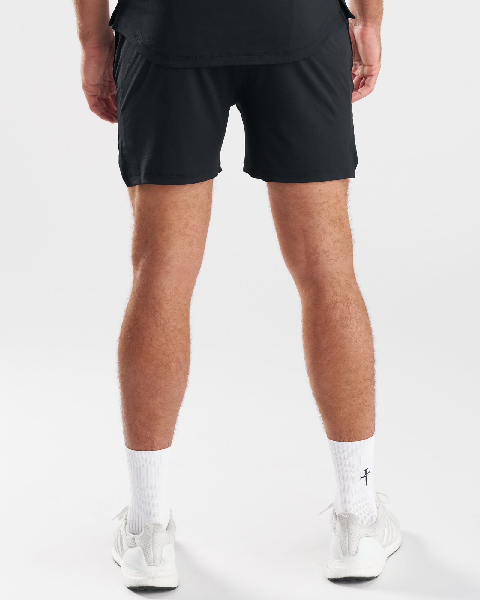 Back view of a male model wearing the Pro-Tech 2.0 Liner Short in black with white sneakers and socks.