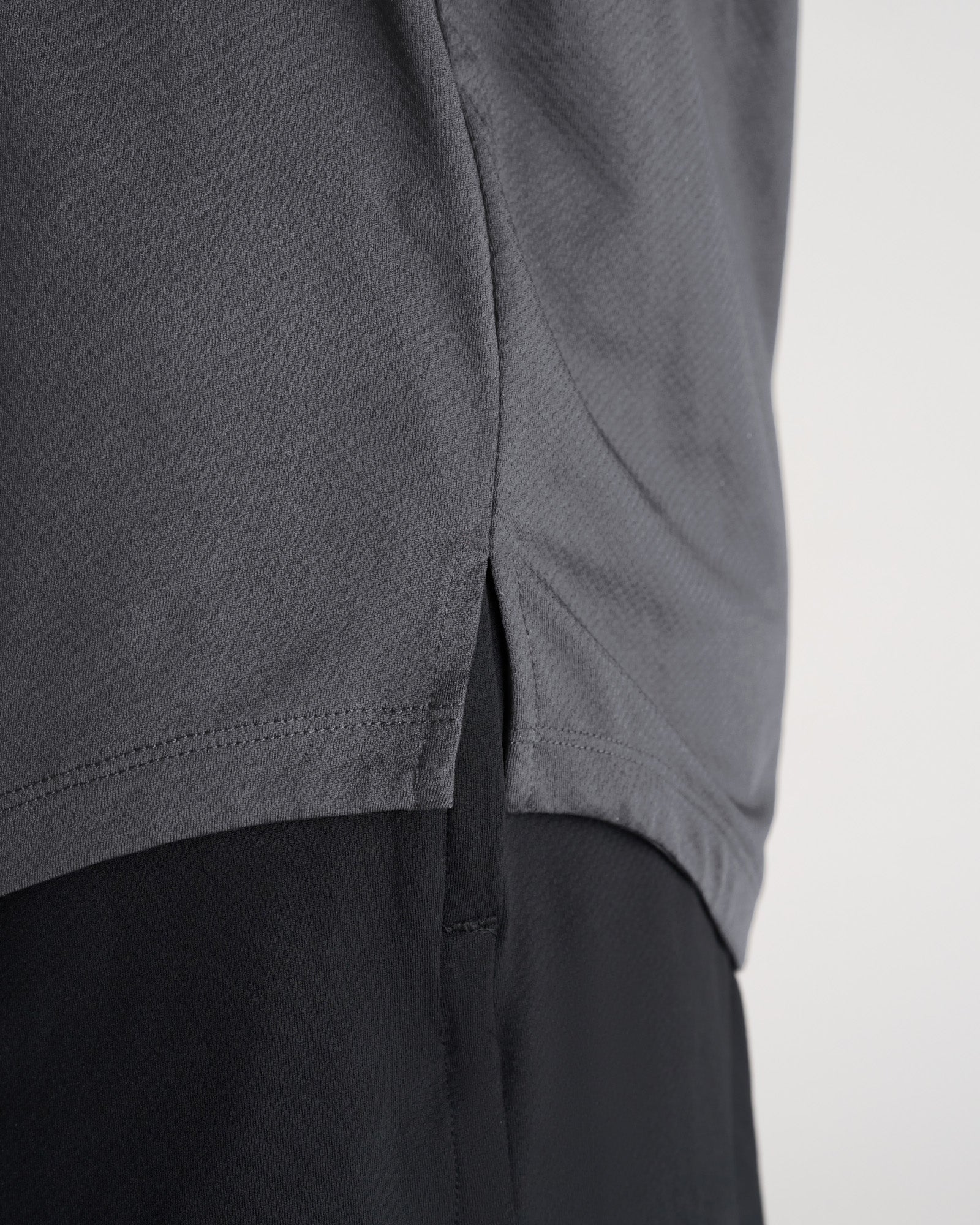 Close-up of the Pro-Tech Tee Cross in Space Grey showing the curved hem and side seam vent detail.