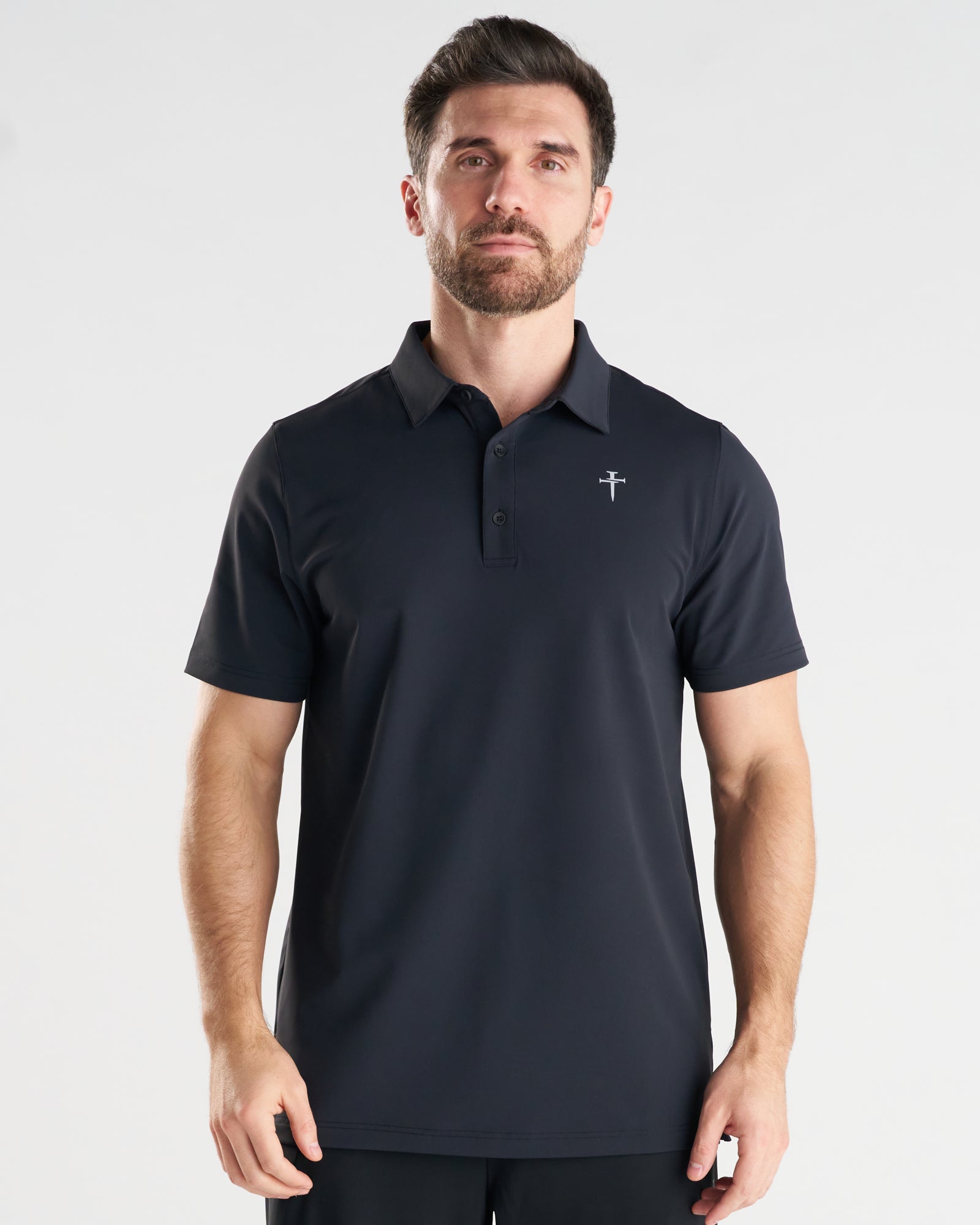 Man wearing black Vented Tech Polo, front view, with small cross logo on chest.