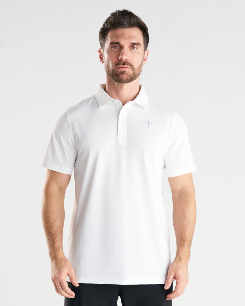 Man wearing white Vented Tech Polo, front view, featuring subtle cross logo and button placket.