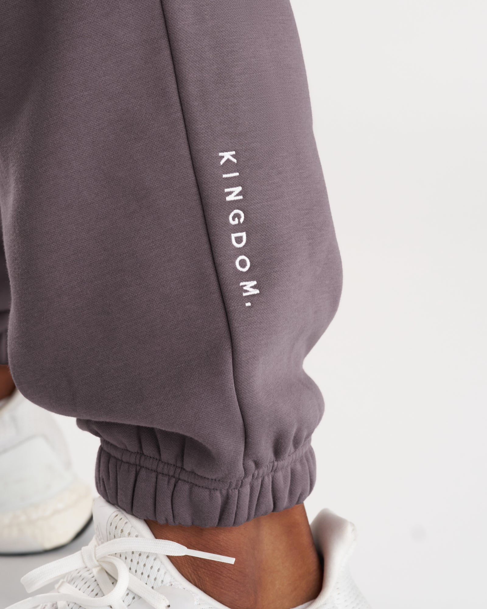 Close-up of Signature Fleece Sweatpants in Moonscape showing the ribbed cuff and embroidered KINGDOM. text on the leg.