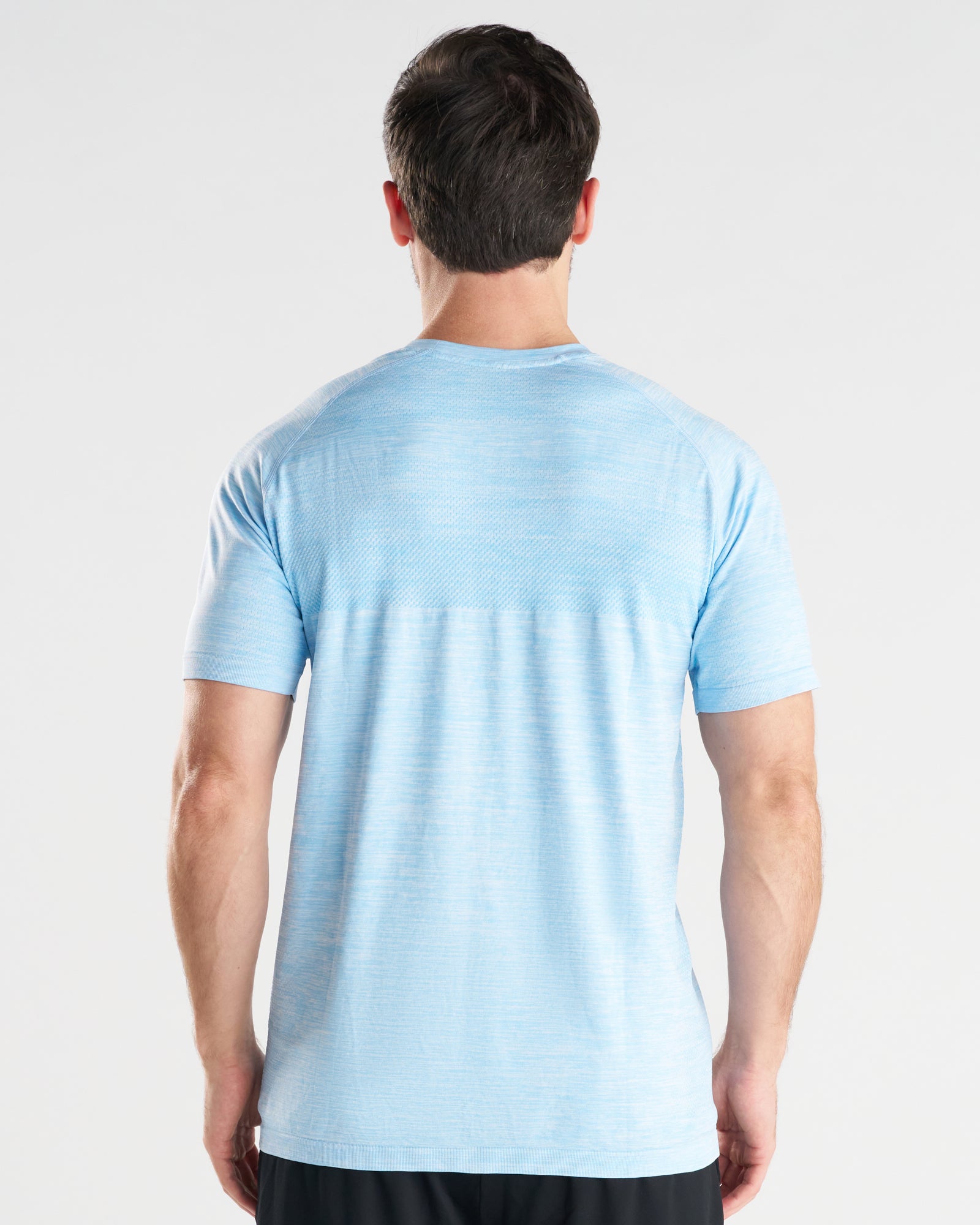 Back view of a male model wearing the Seamless Tee in Sky Blue, showing textured fabric and raglan sleeves.