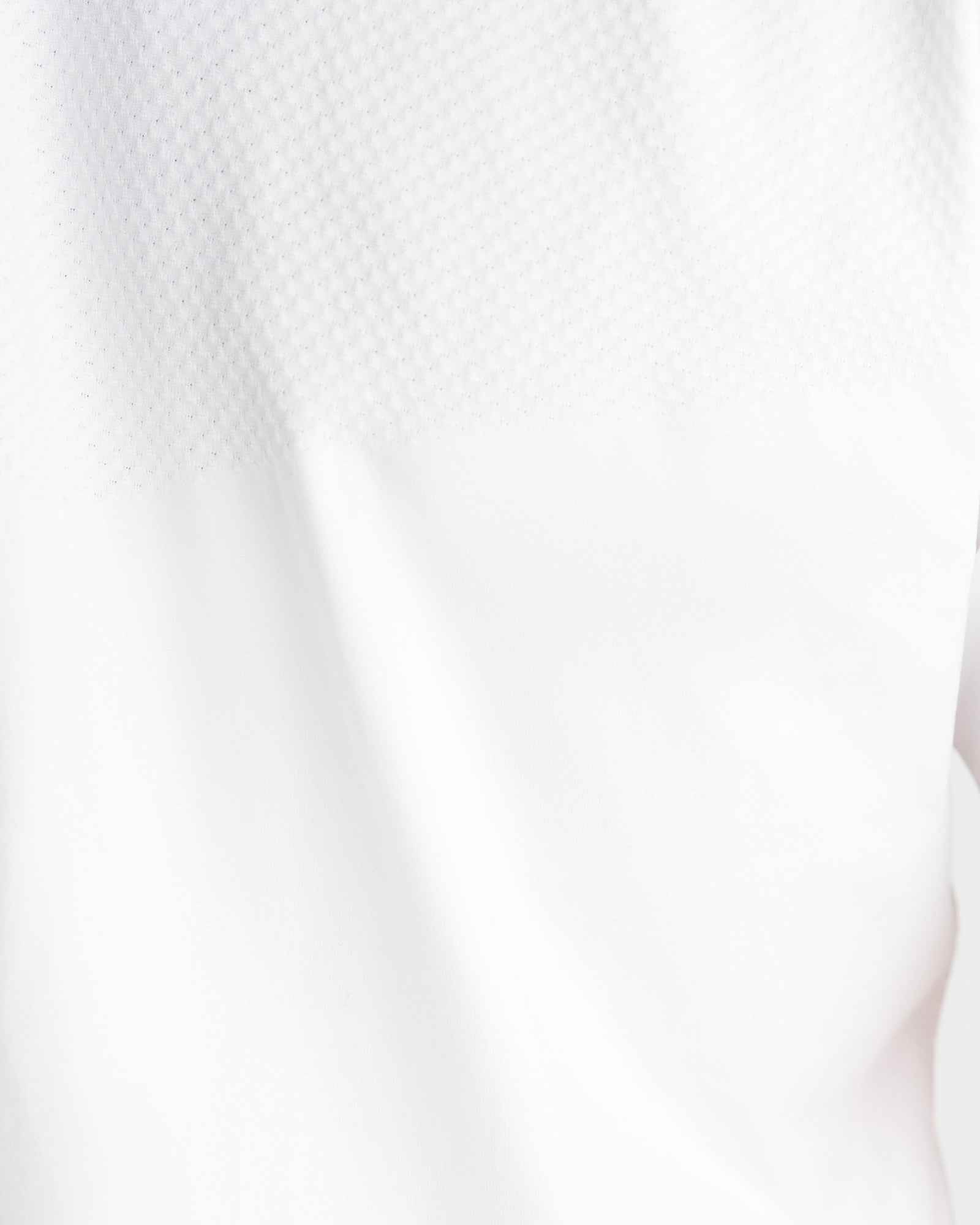 Close-up detail of the Seamless Tee in White showing textured mesh fabric and smooth panel contrast.