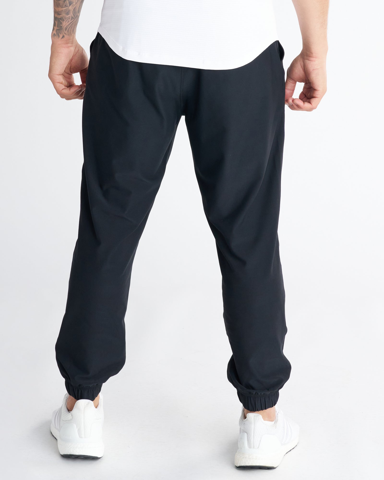 Back view of Haven Performance Jogger in black with elastic cuffs, worn with white sneakers.