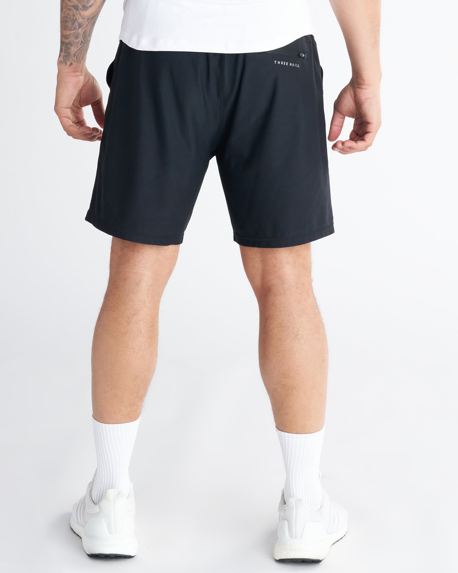 Back view of Haven Performance Short in black on a standing male model with white sneakers.