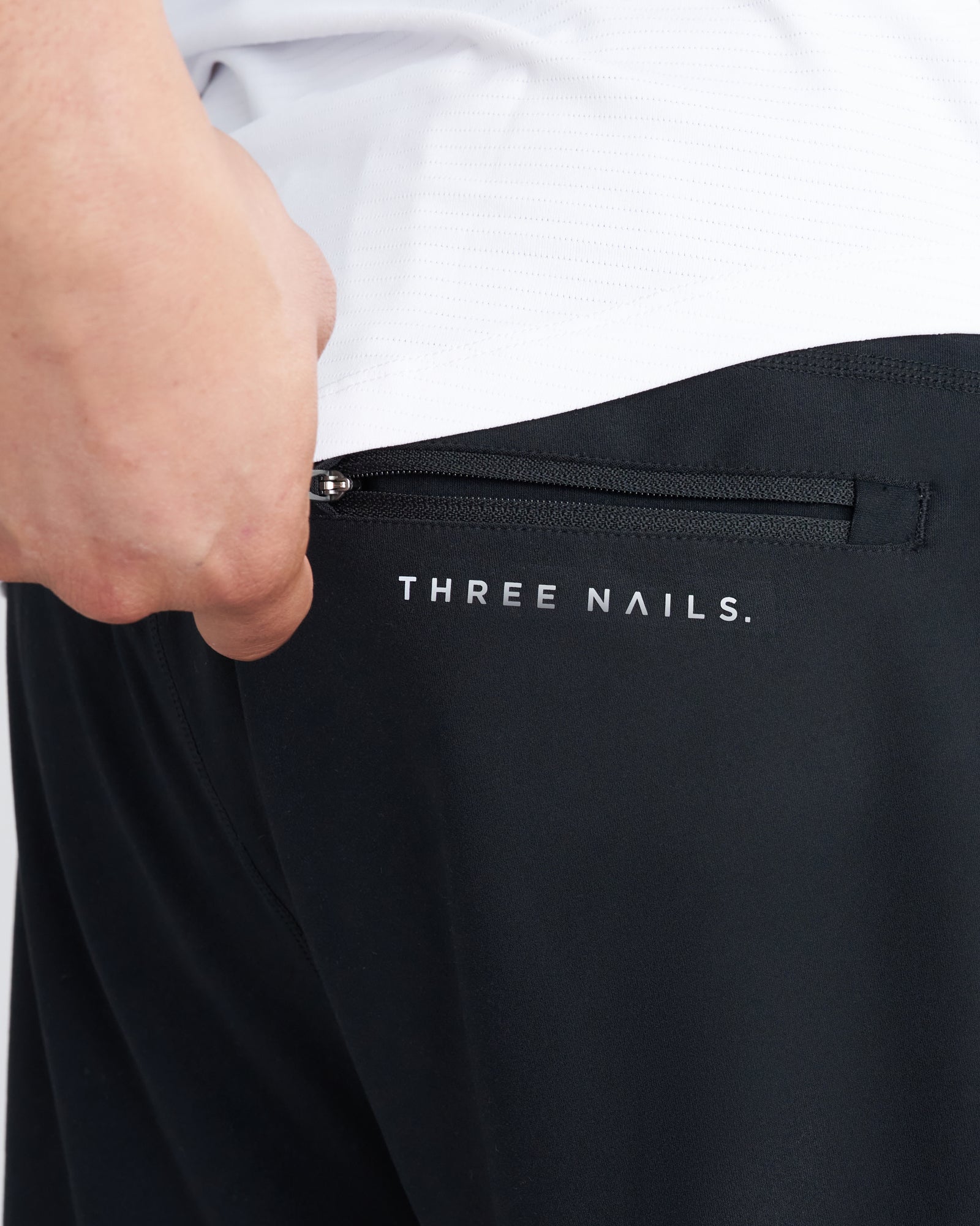 Close-up of Haven Performance Short in black showing zippered side pocket with Three Nails branding.