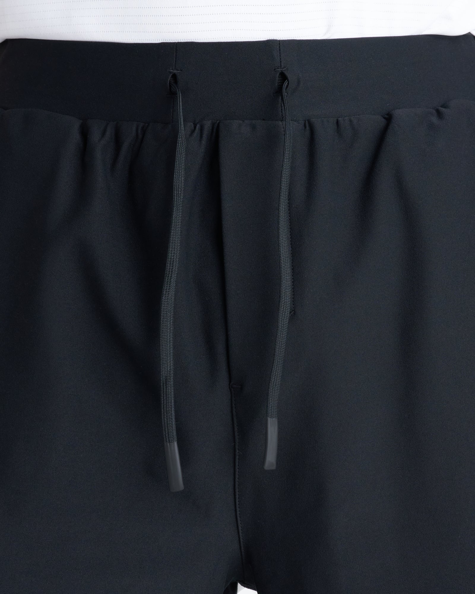 Close-up of Haven Performance Short in black showing elastic waistband and dual dark drawstrings with tipped ends.