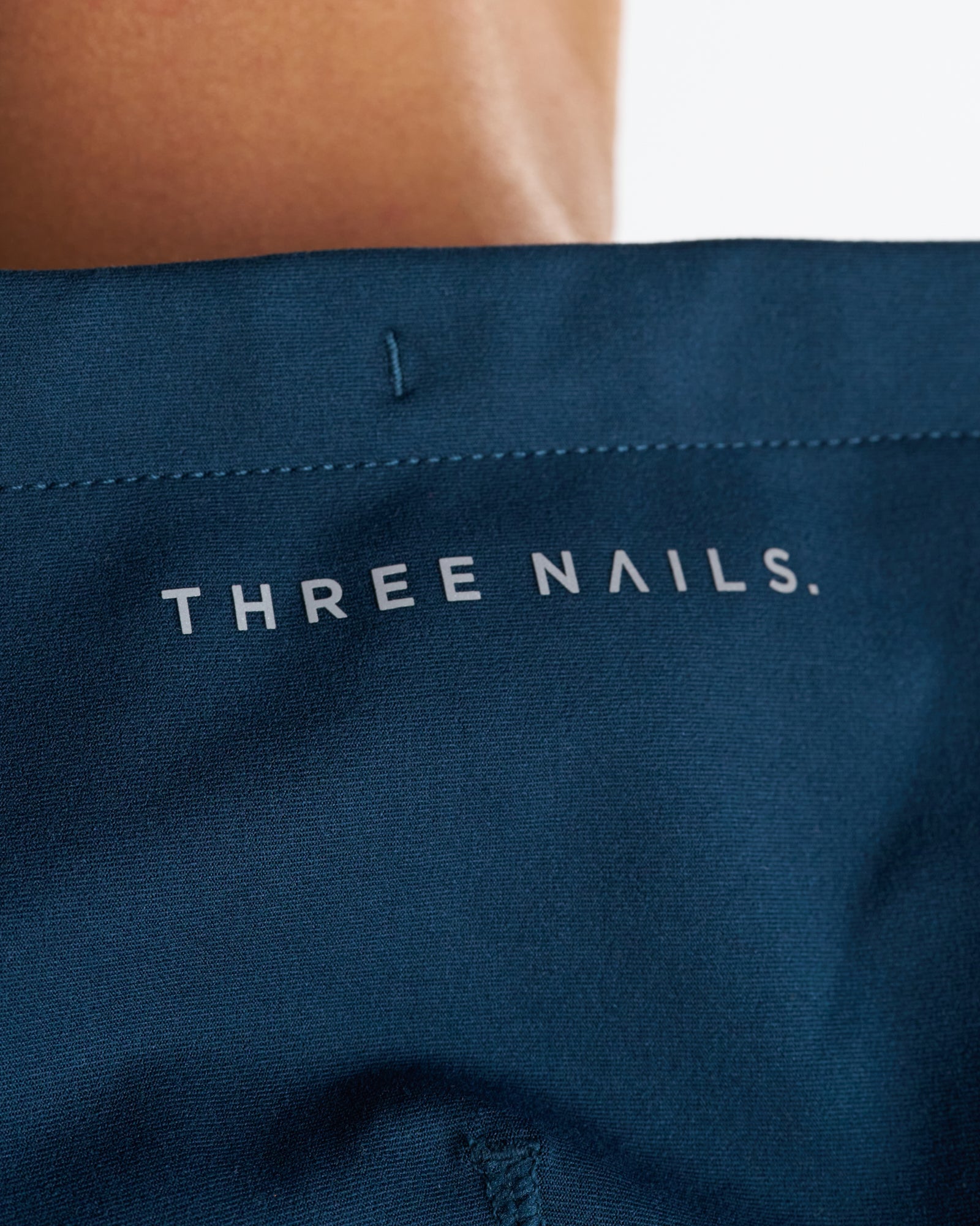 Close-up of the interior waistband label on the Haven Performance Hoodie in Midnight Navy showing the Three Nails wordmark.