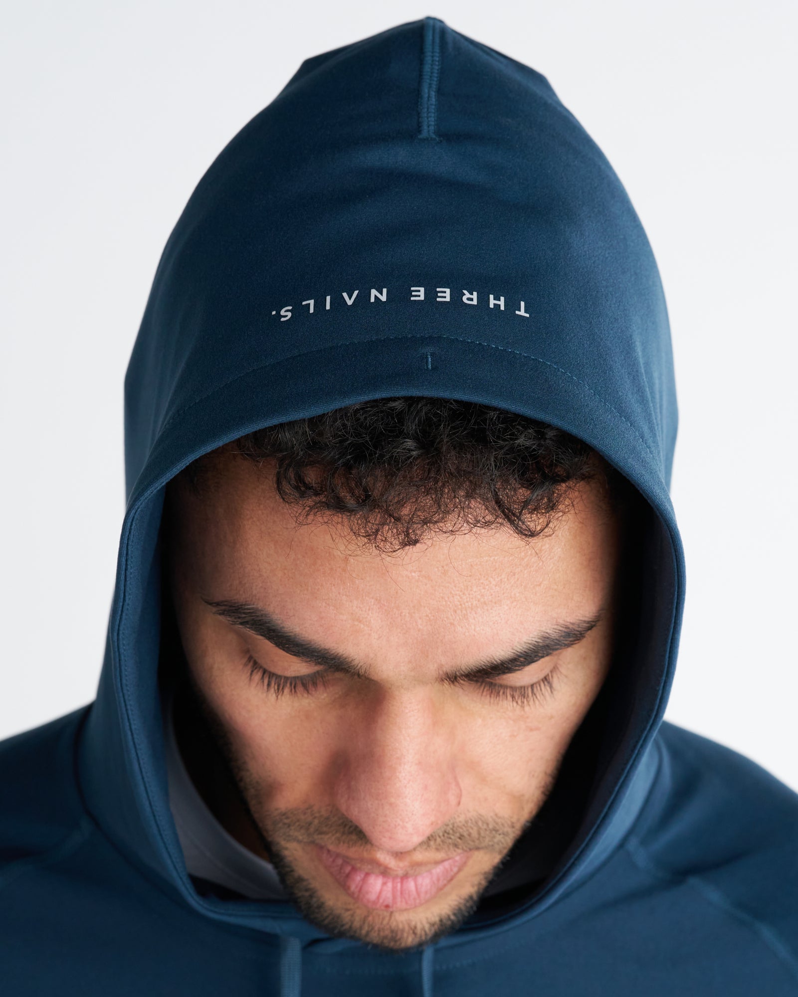 Close-up of model wearing Haven Performance Hoodie in Midnight Navy showing hood detail with Three Nails branding.