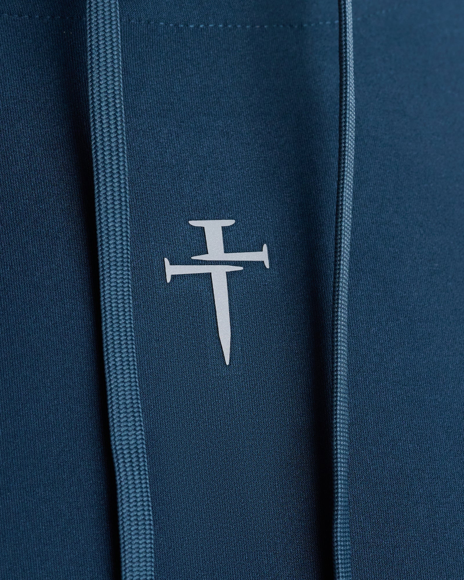 Close-up of the Three Nails logo detail on the Haven Performance Hoodie in Midnight Navy.