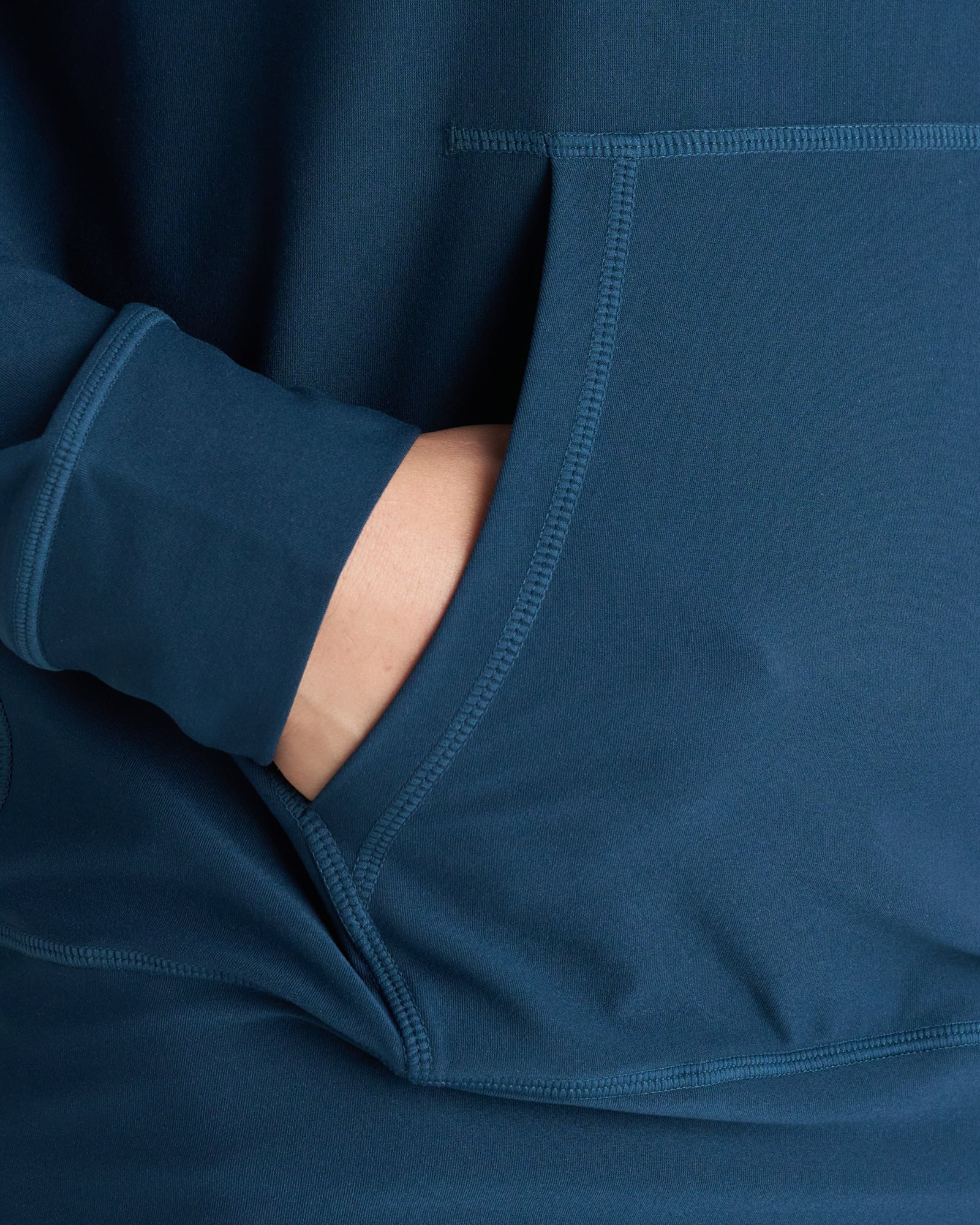 Close-up detail of the Haven Performance Hoodie in Midnight Navy showing the kangaroo pocket with a hand tucked inside.