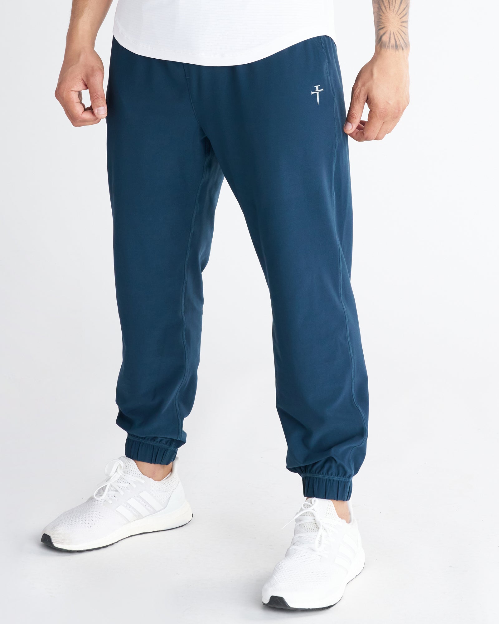 Haven Performance Jogger in Midnight Navy on a front-facing model with elastic cuffs and a small cross logo.