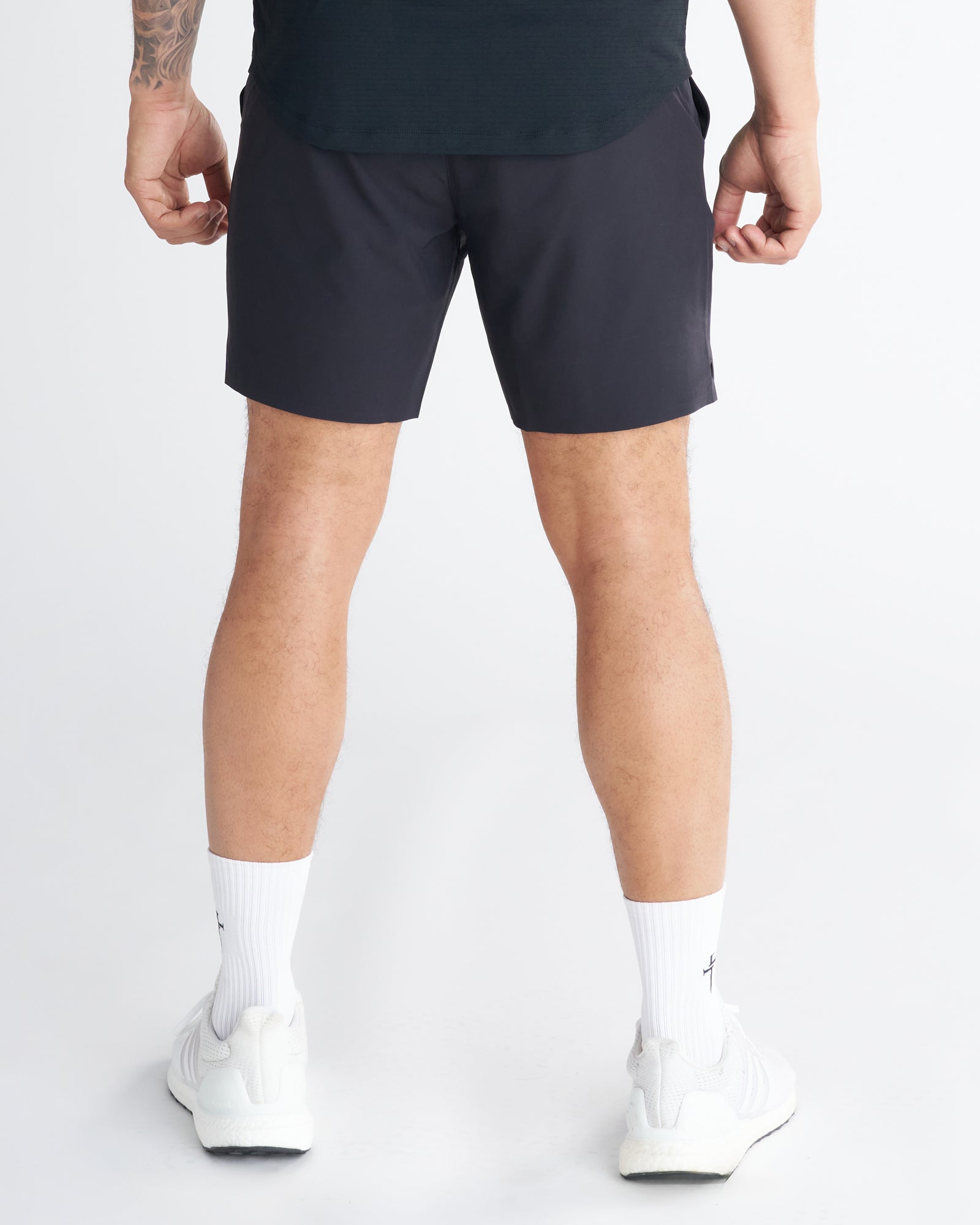 Back view of a model wearing the Pulse Tech Linerless Short in black with white sneakers and socks.