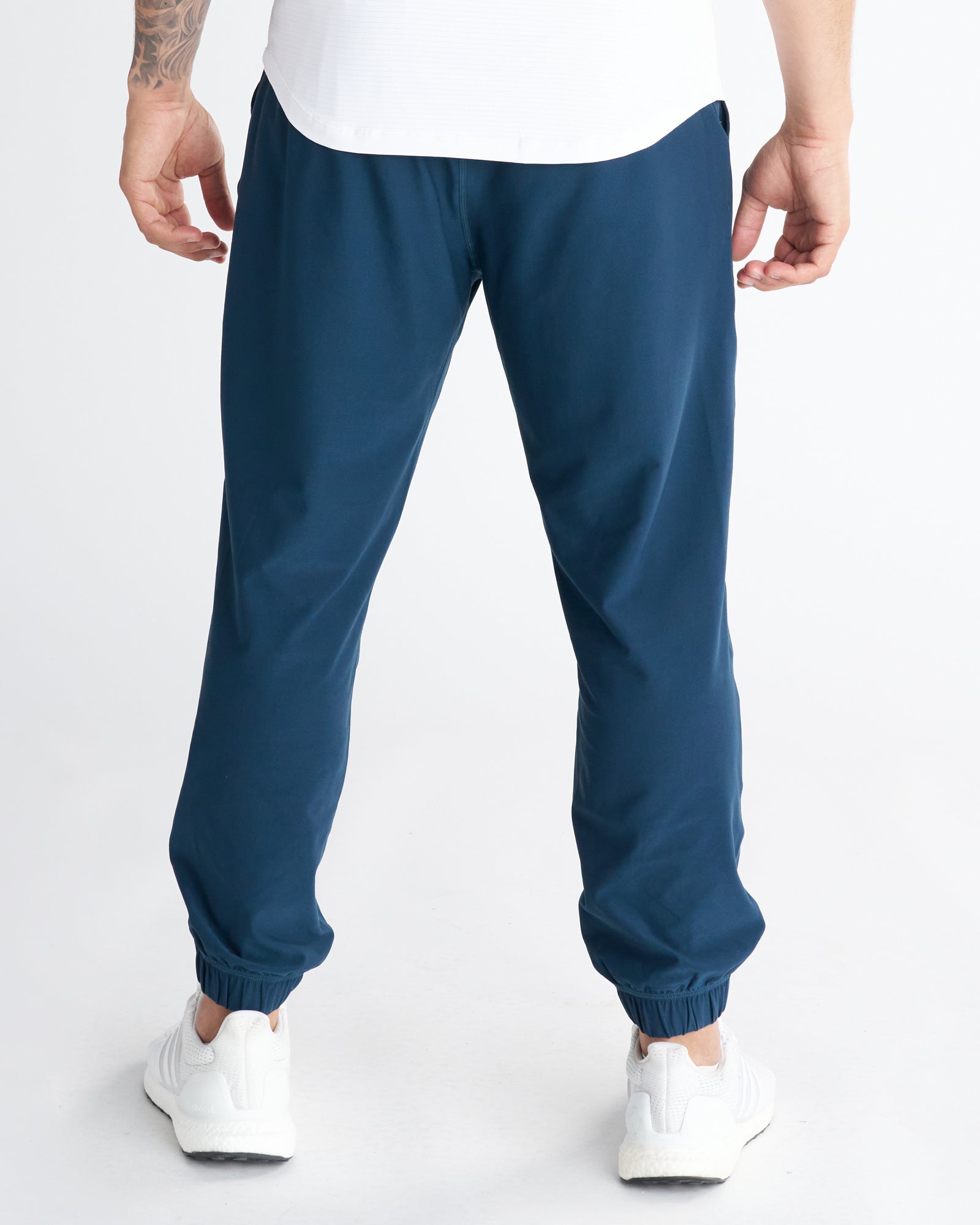 Back view of the Haven Performance Jogger in Midnight Navy with ribbed ankle cuffs, paired with white sneakers.