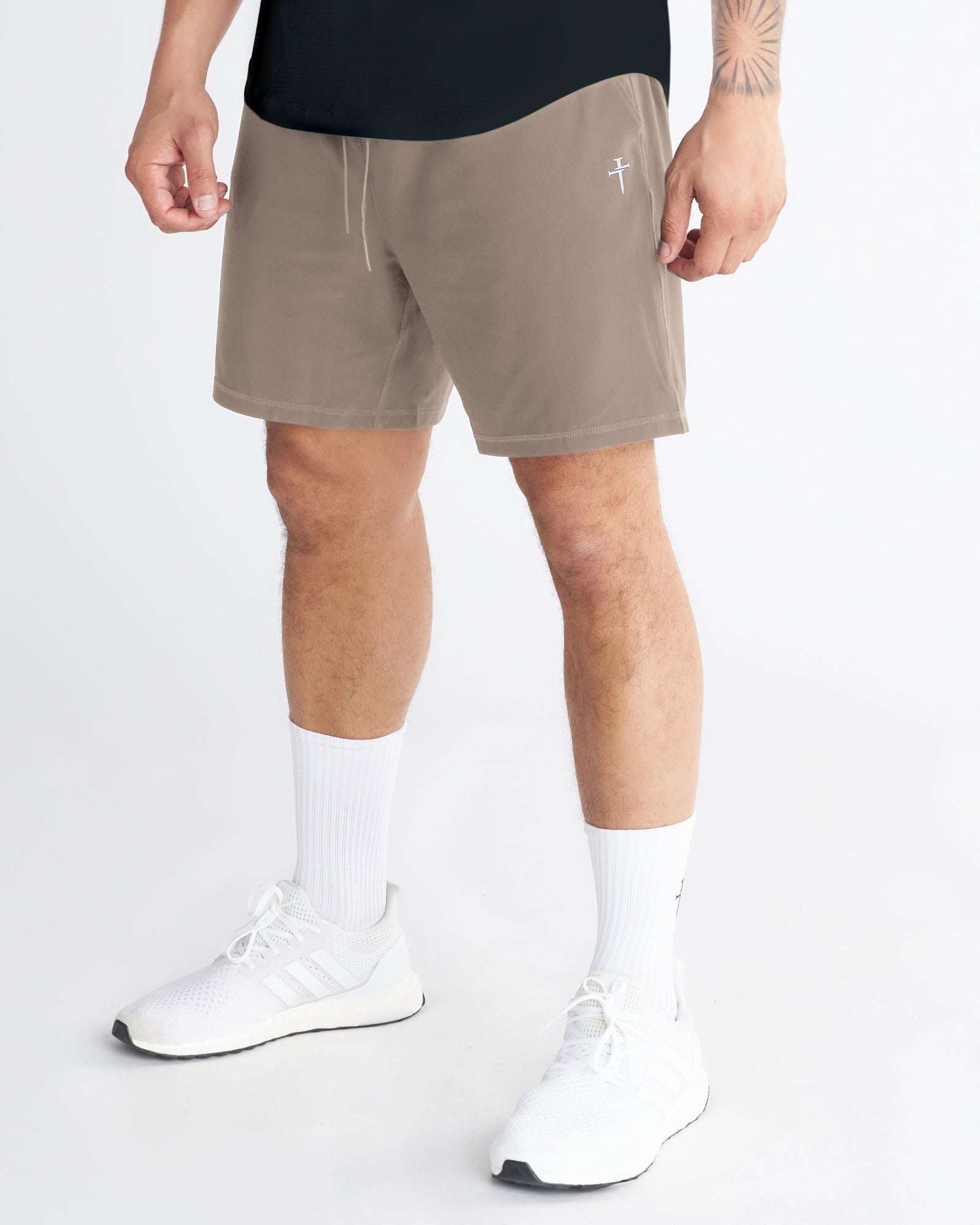 Haven Performance Short in Sand on a model at a slight angle, showing tan shorts with white drawstring and small logo.