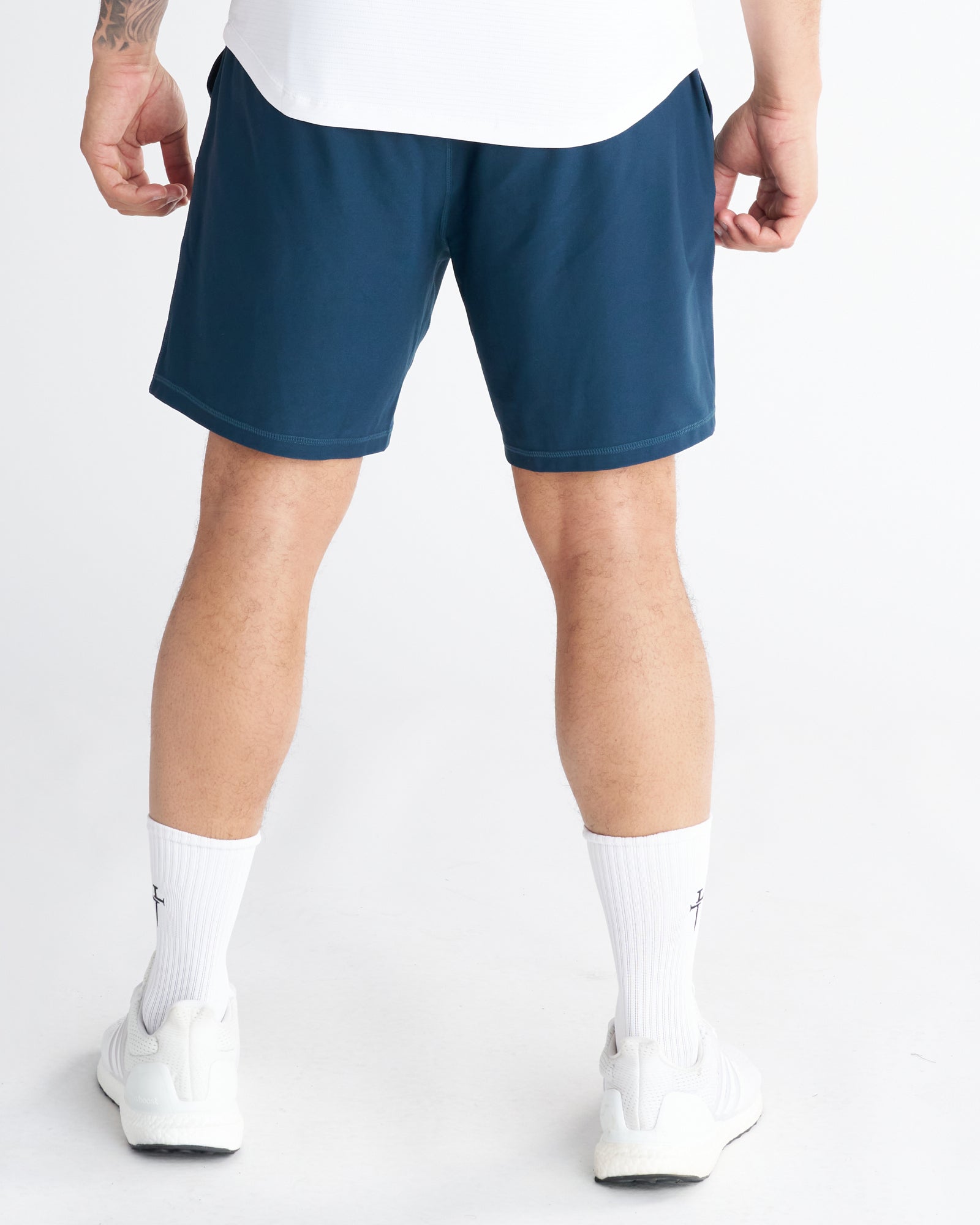 Back view of Haven Performance Short in Midnight Navy worn by a male model with white sneakers and socks.