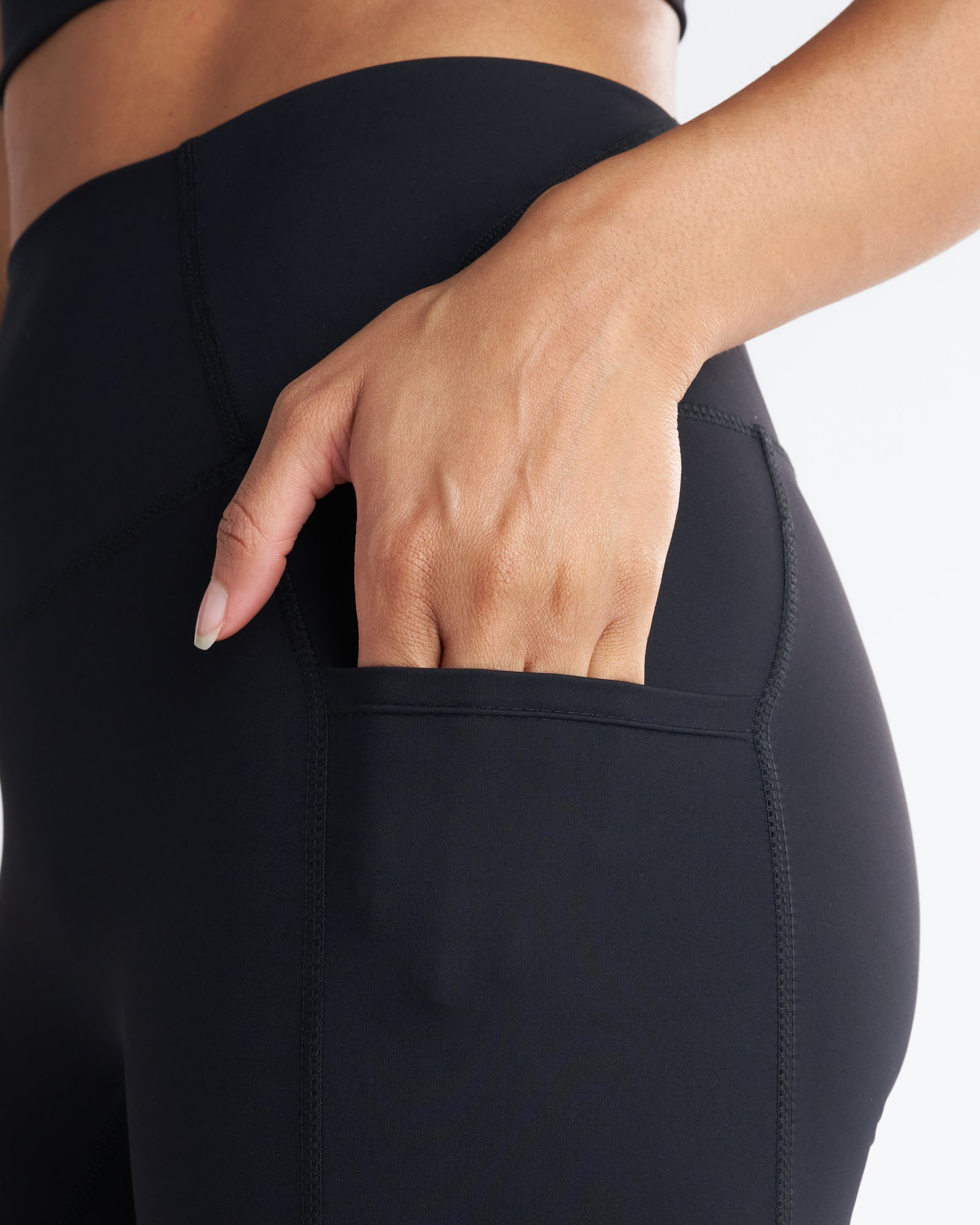 Close-up detail of the Endura-Train Pocket Legging in black showing a hand sliding into the side thigh pocket.