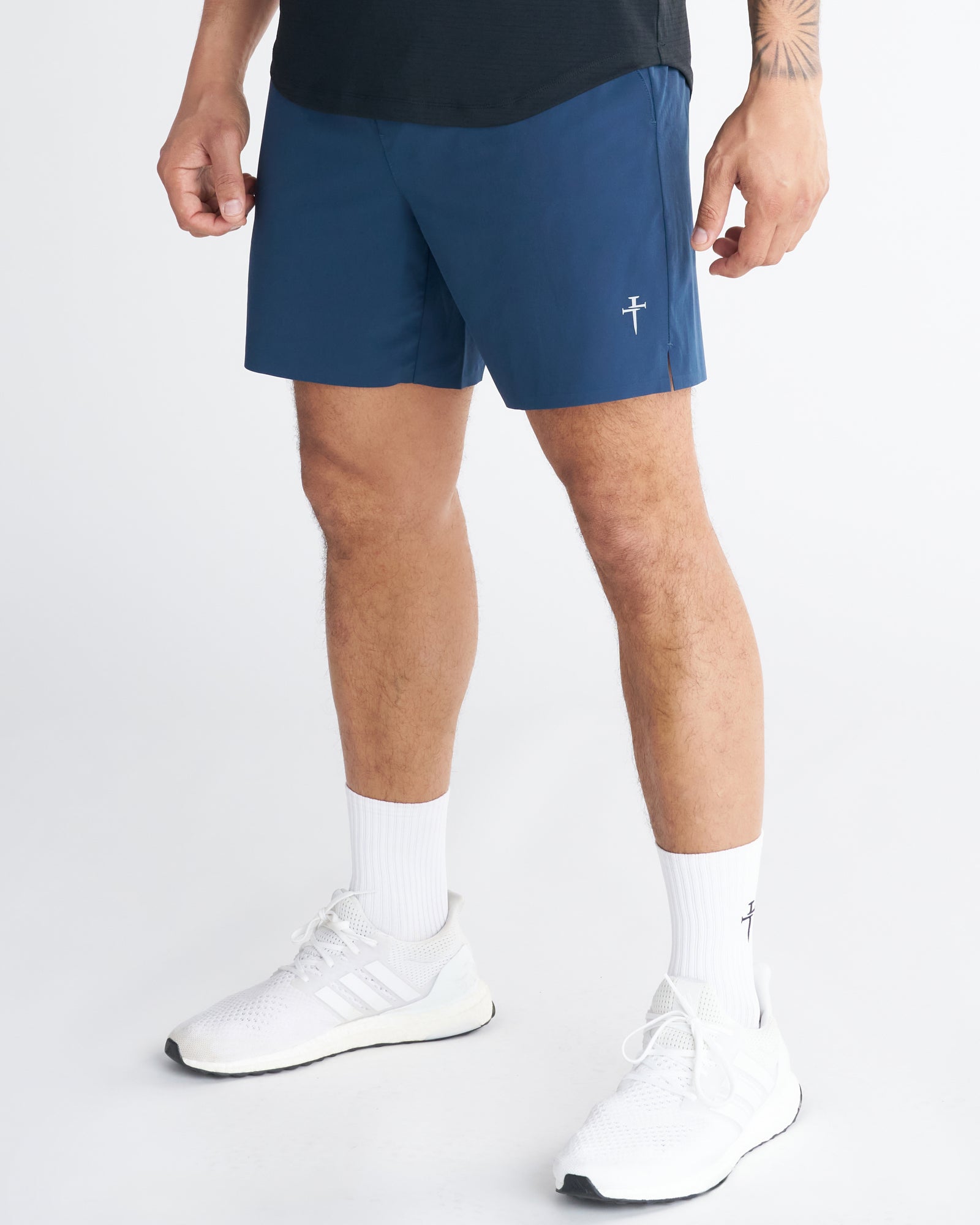 Front side-angle view of the Pulse Tech Linerless Short in Midnight Navy worn with white Adidas sneakers and branded socks.
