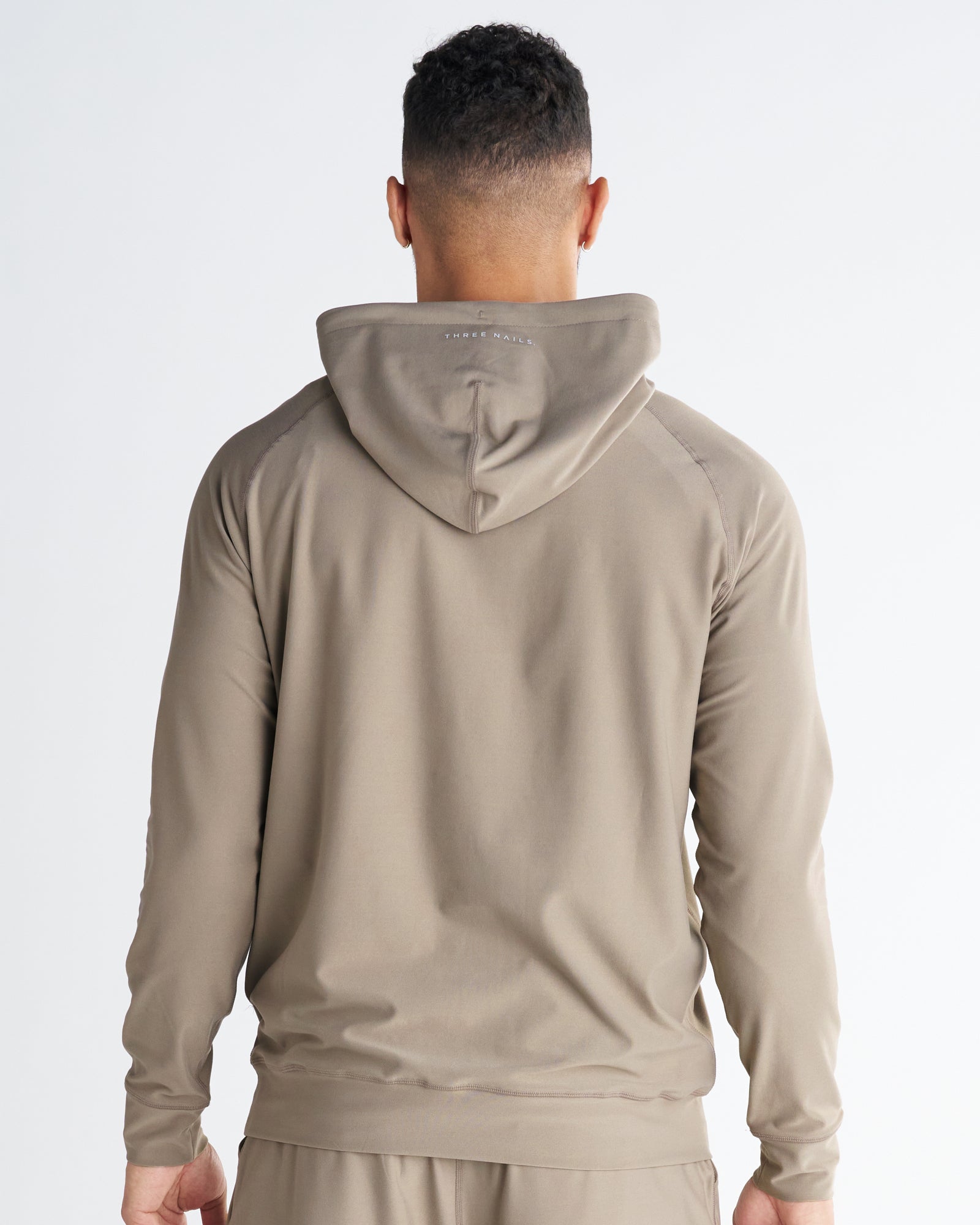 Haven Performance Hoodie in Sand shown from the back view on a male model wearing matching shorts.