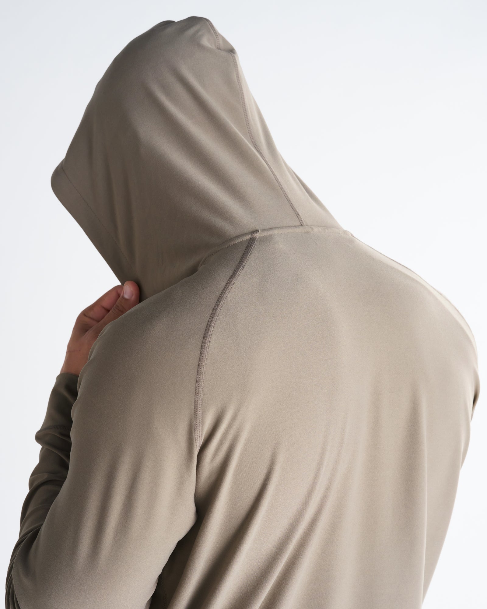 Haven Performance Hoodie in Sand shown from behind on a model with hood up, highlighting back seam detail.