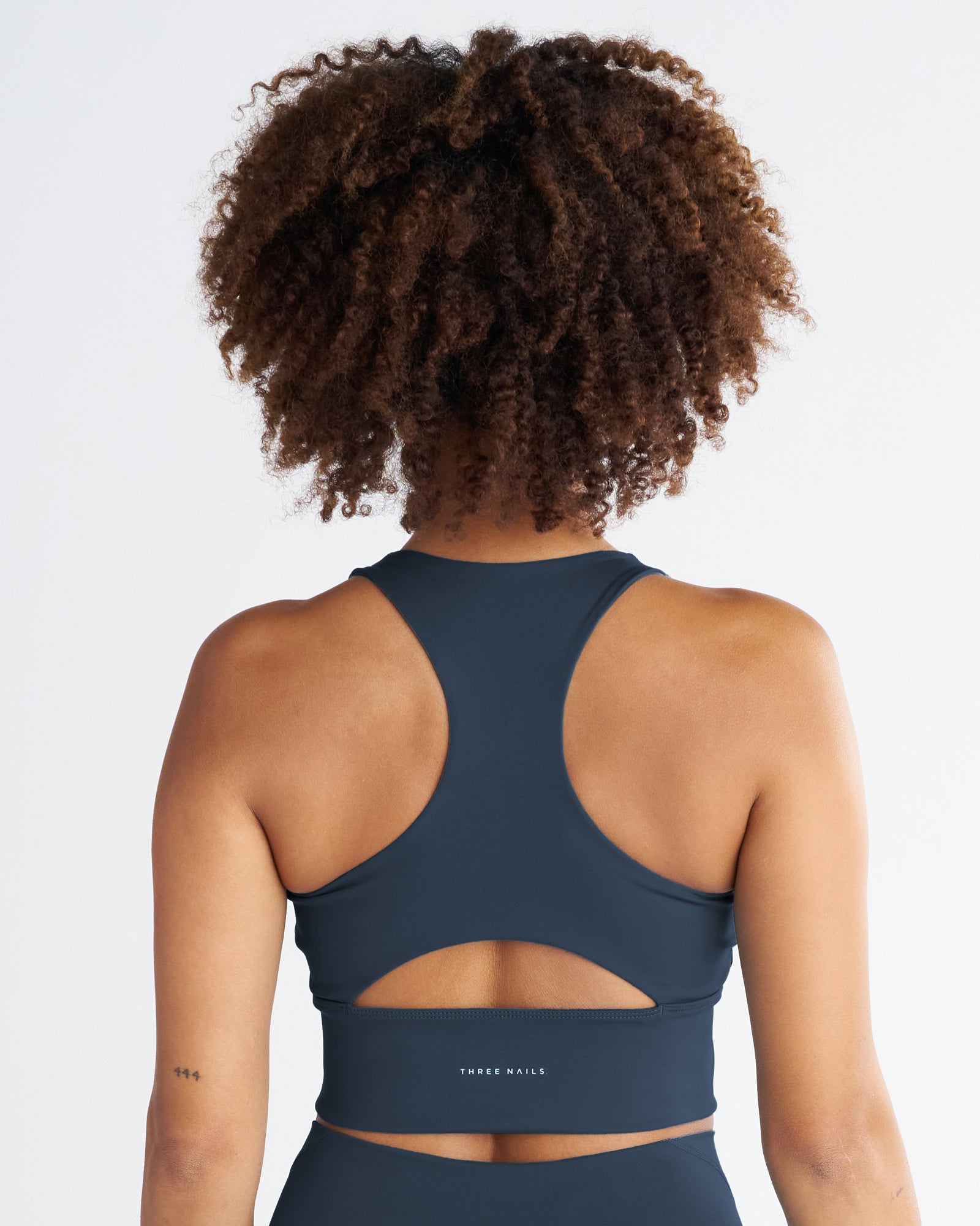 Back view of the Endura-Train Longline Bra in Midnight Navy, showing racerback design and cutout waist detail.