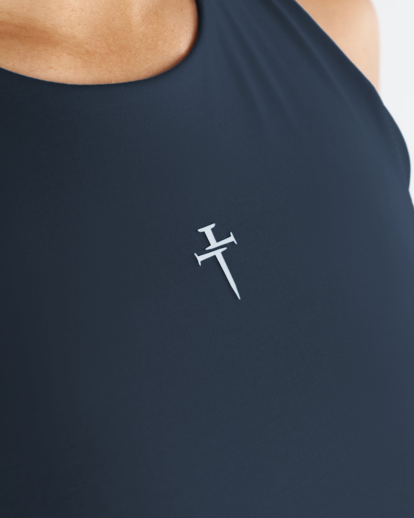 Close-up detail of the Endura-Train Longline Bra in Midnight Navy showing the small Three Nails logo on the chest.