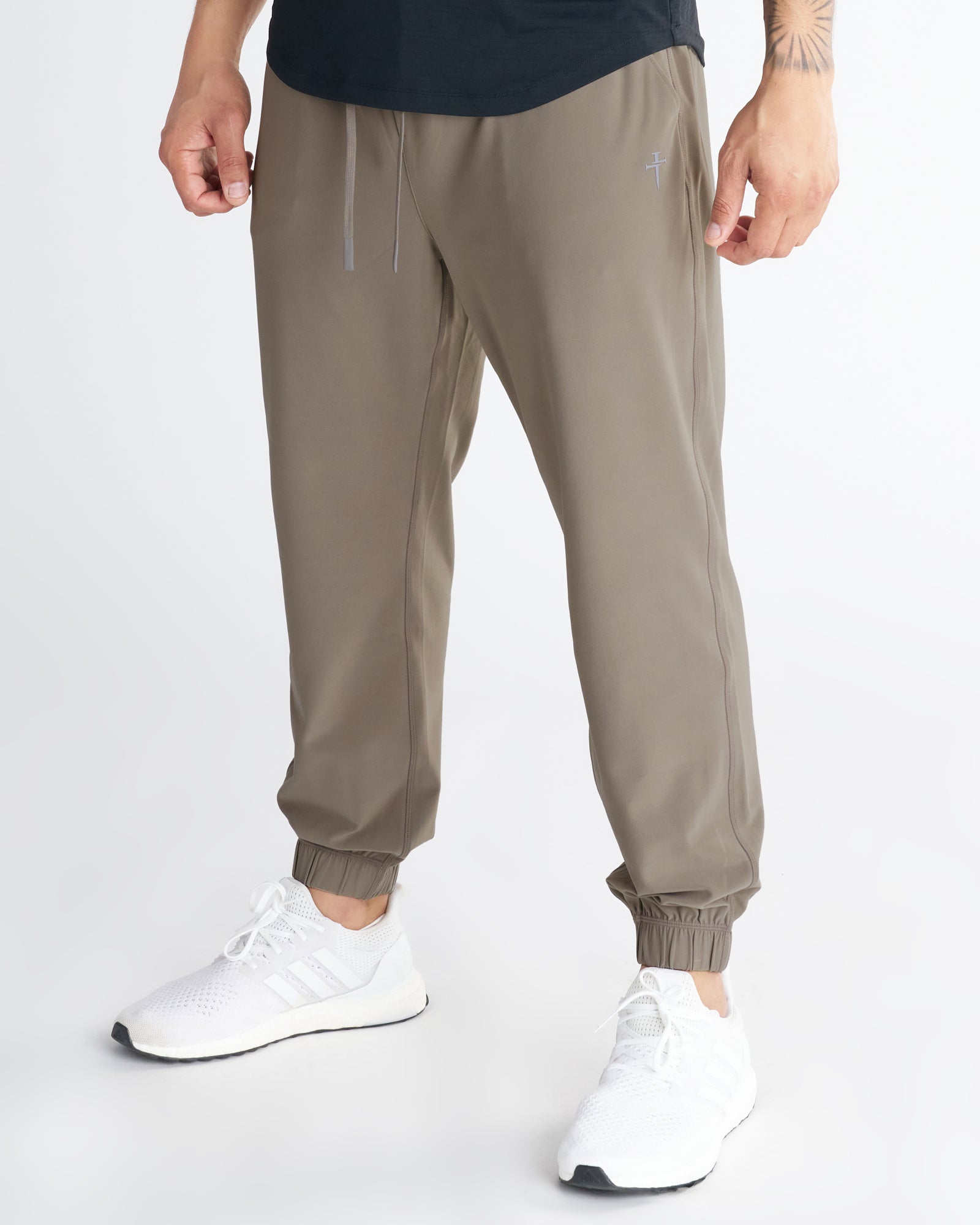 Haven Performance Jogger in Sand worn by a male model, front angled view, showing tapered fit and elastic cuffs.