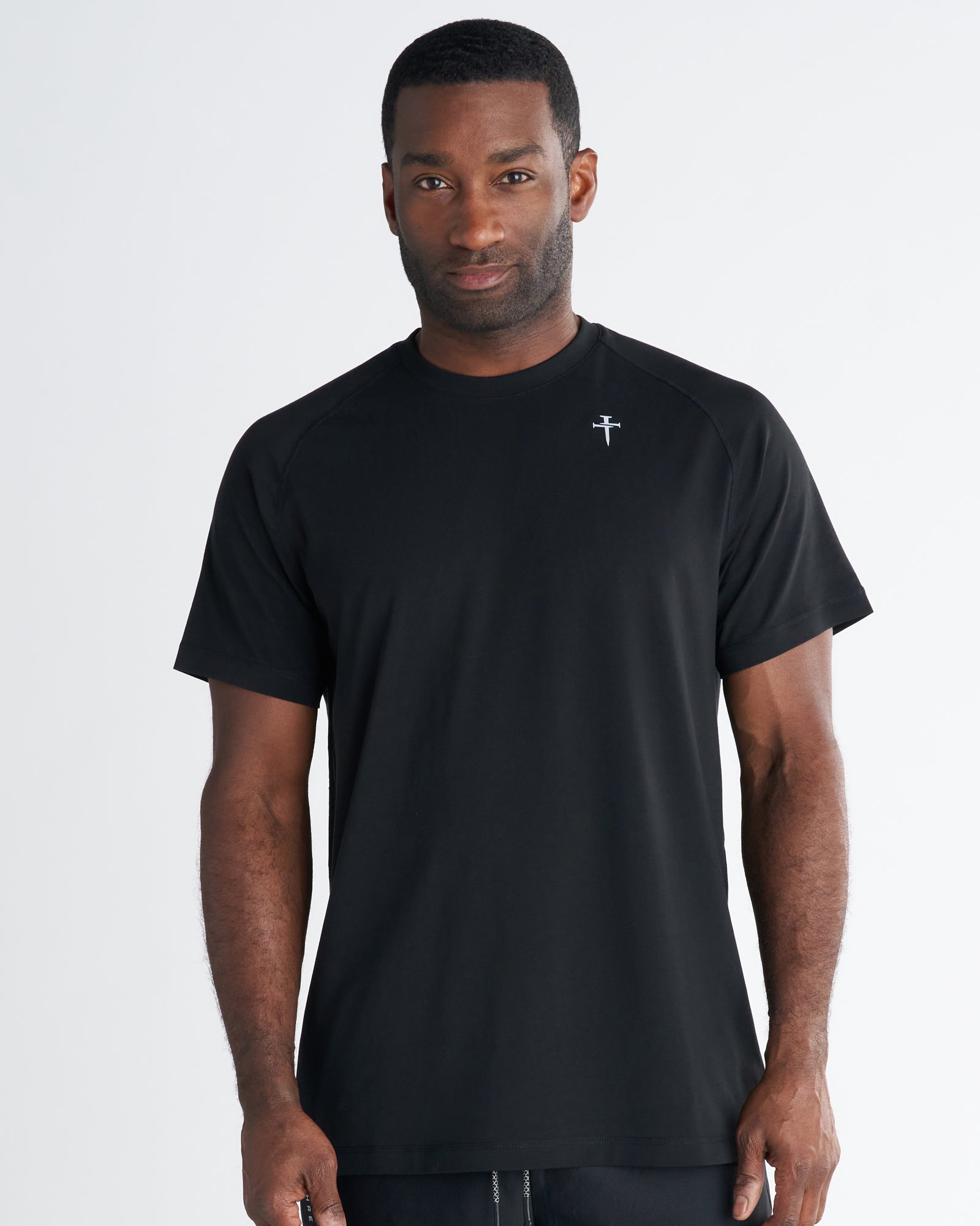 Man wearing the Core Tee in black, front view, featuring a small logo on the chest and raglan sleeves.