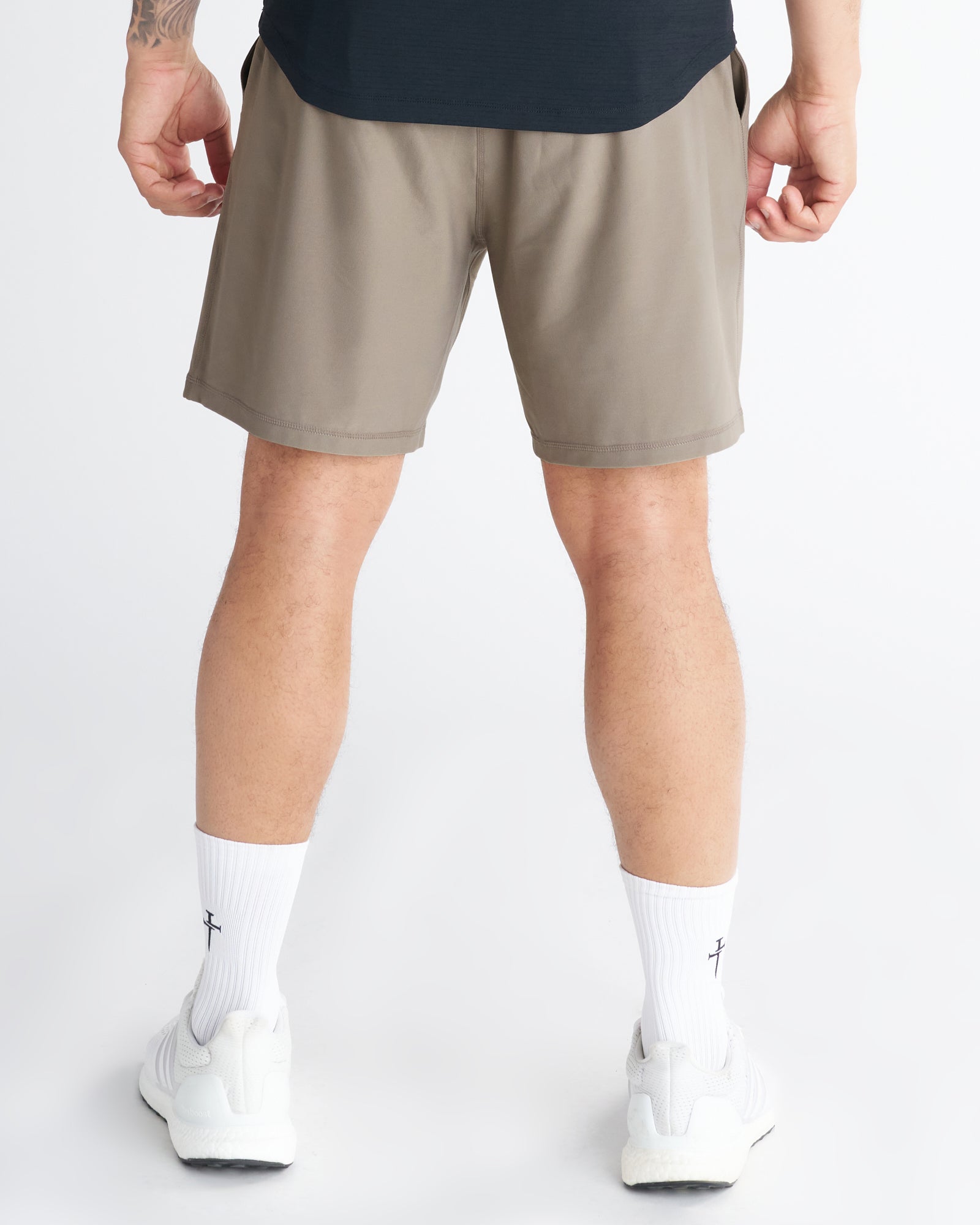 Back view of Haven Performance Short in Sand worn by a male model with white sneakers and socks.
