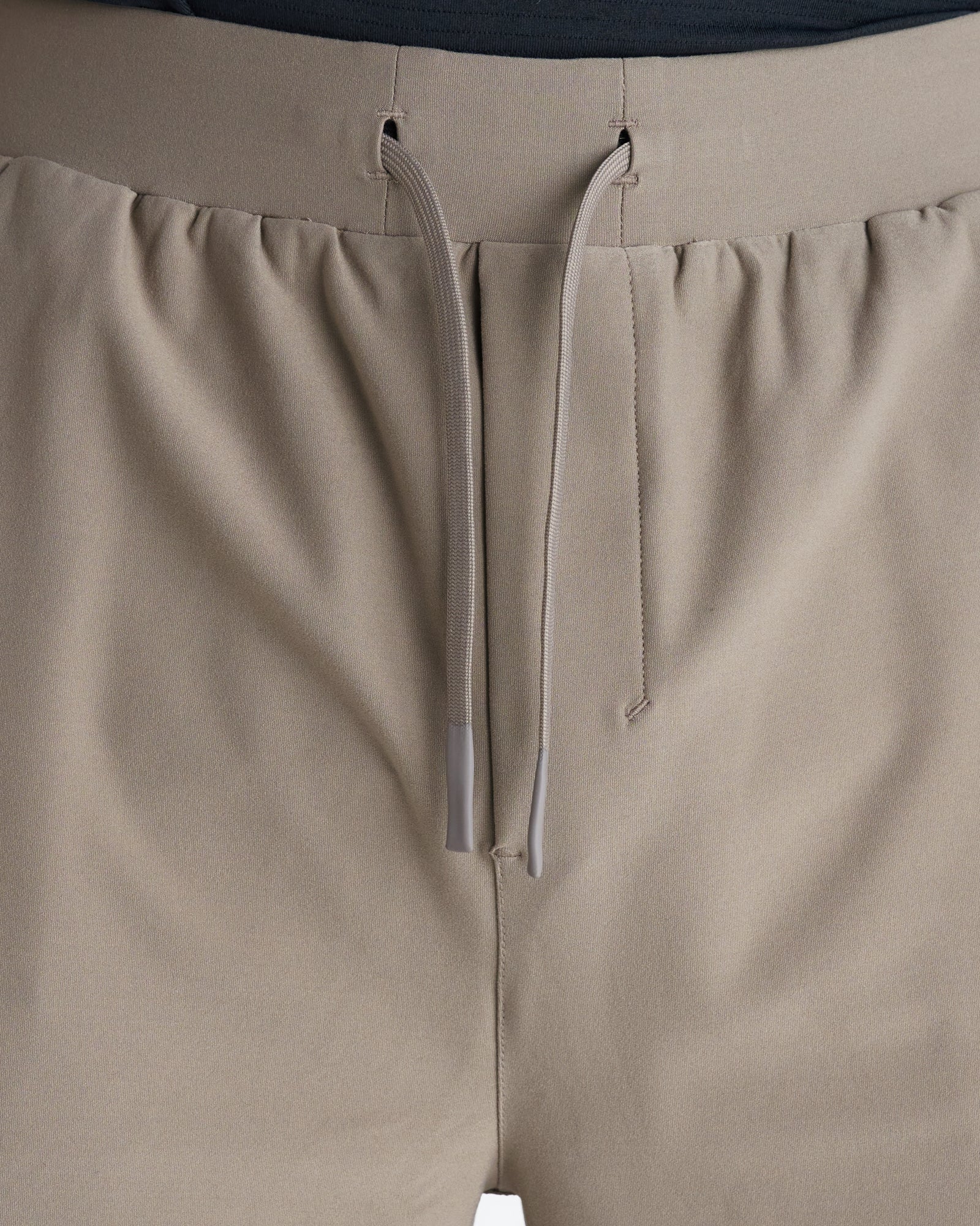 Close-up of Haven Performance Short in Sand showing elastic waistband, twin drawstring eyelets, and tonal drawcord with gray tips.