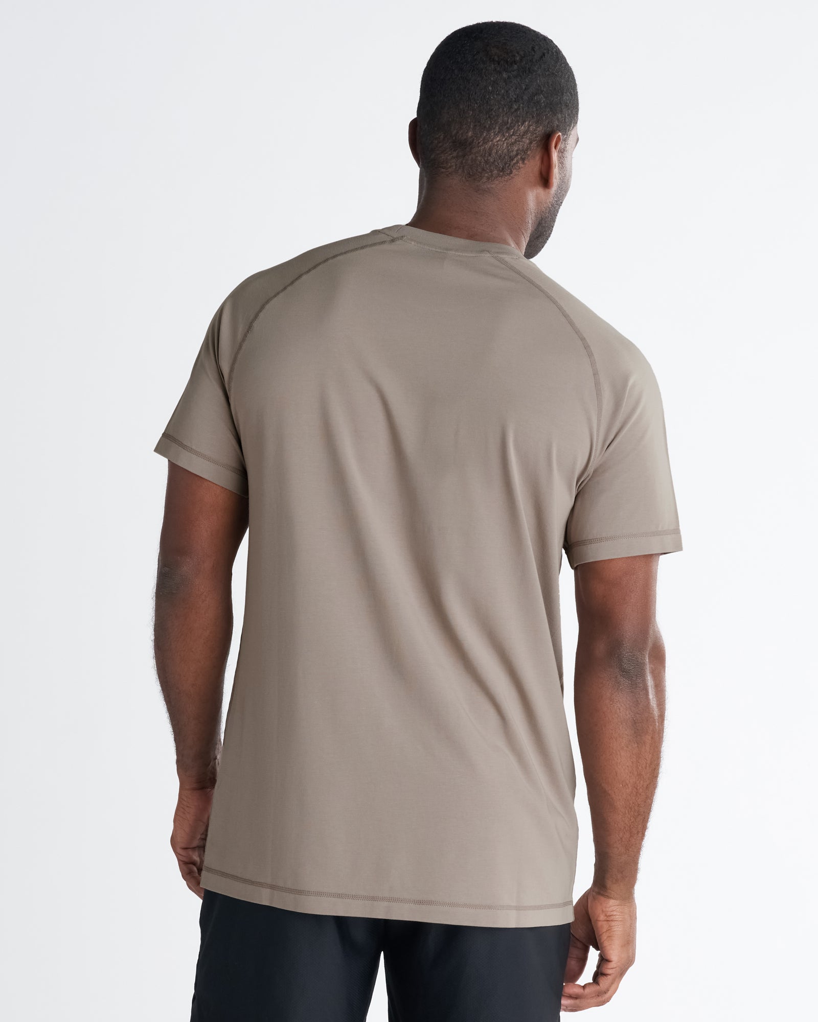 Back view of a male model wearing the Core Tee in Sand, a taupe short-sleeve tee with raglan seams.
