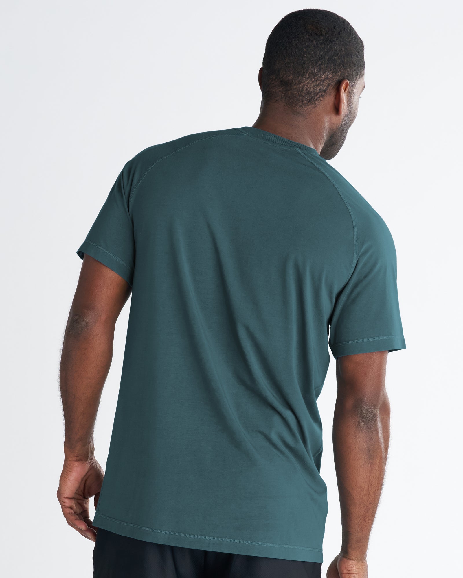 Back view of a man wearing the Core Tee in teal, a plain short-sleeve t-shirt with raglan-style seams.