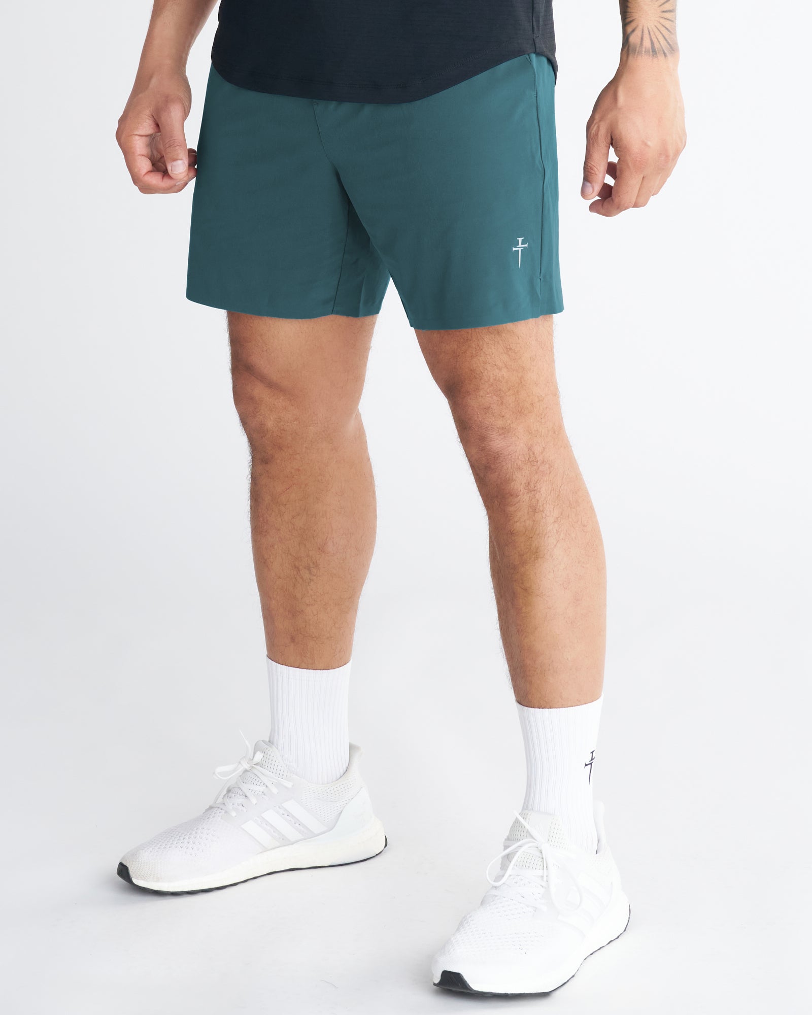 Side angle view of the Pulse Tech Linerless Short in Teal, paired with white Adidas sneakers and crew socks.