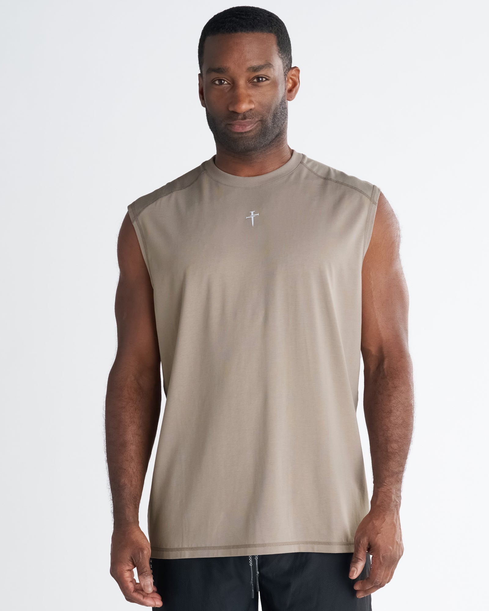 Man wearing Core Raglan Cutoff in Sand, front view, with small cross logo at chest.