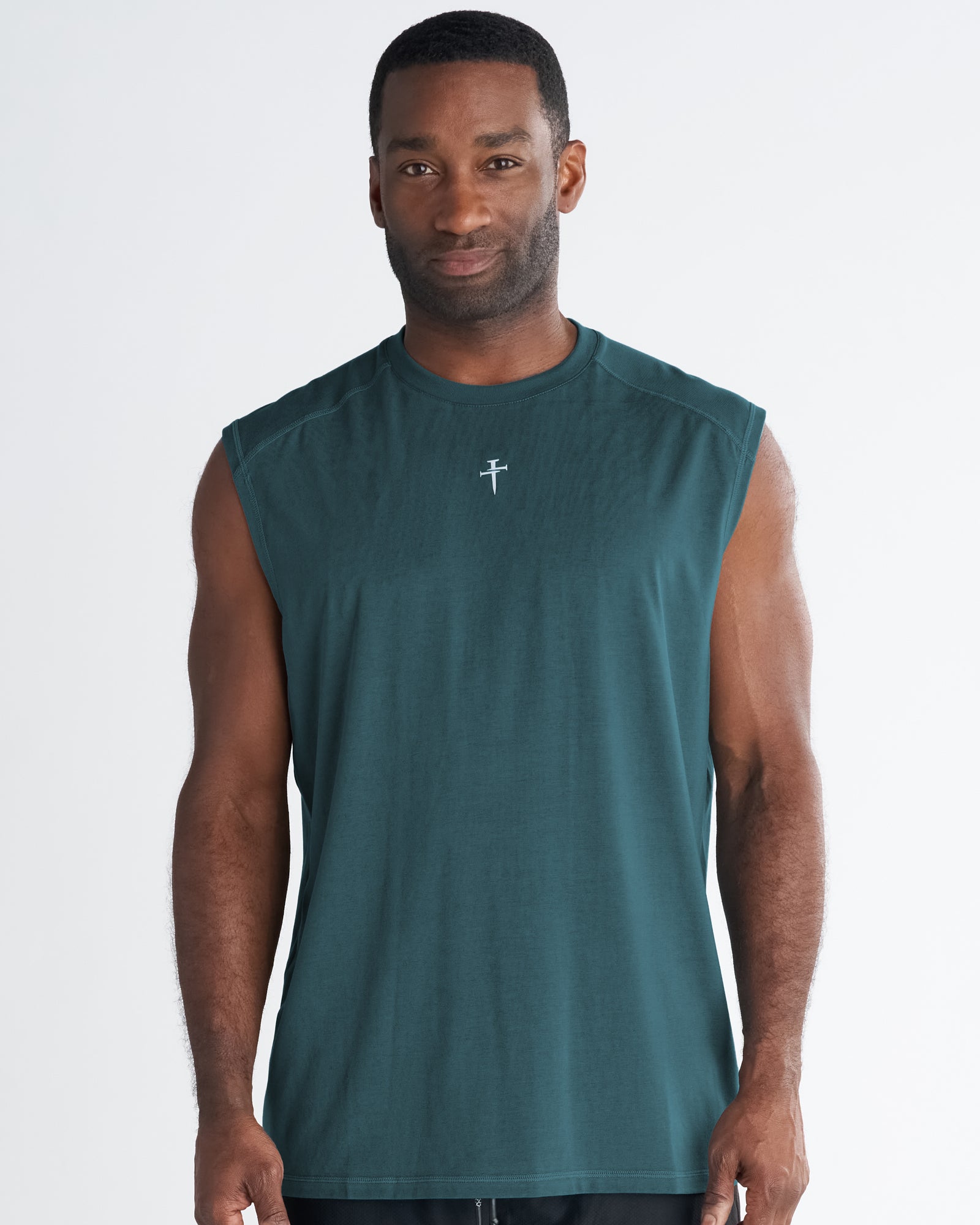 Male model wearing the Core Raglan Cutoff in teal, front view, with a small cross logo on chest.