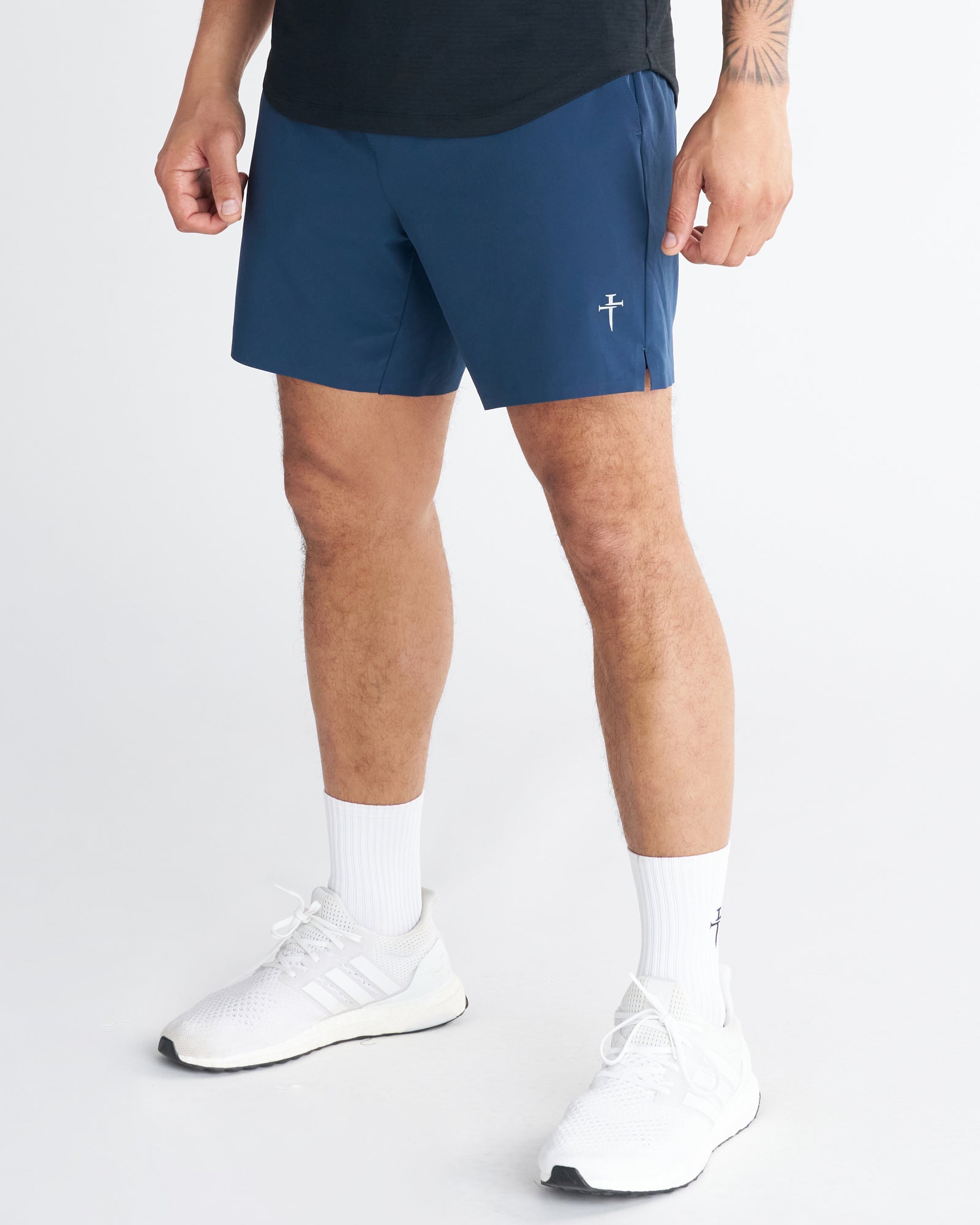 Front side-angle view of the Pulse Tech Liner Short in Midnight Navy, worn with white Adidas sneakers and socks.