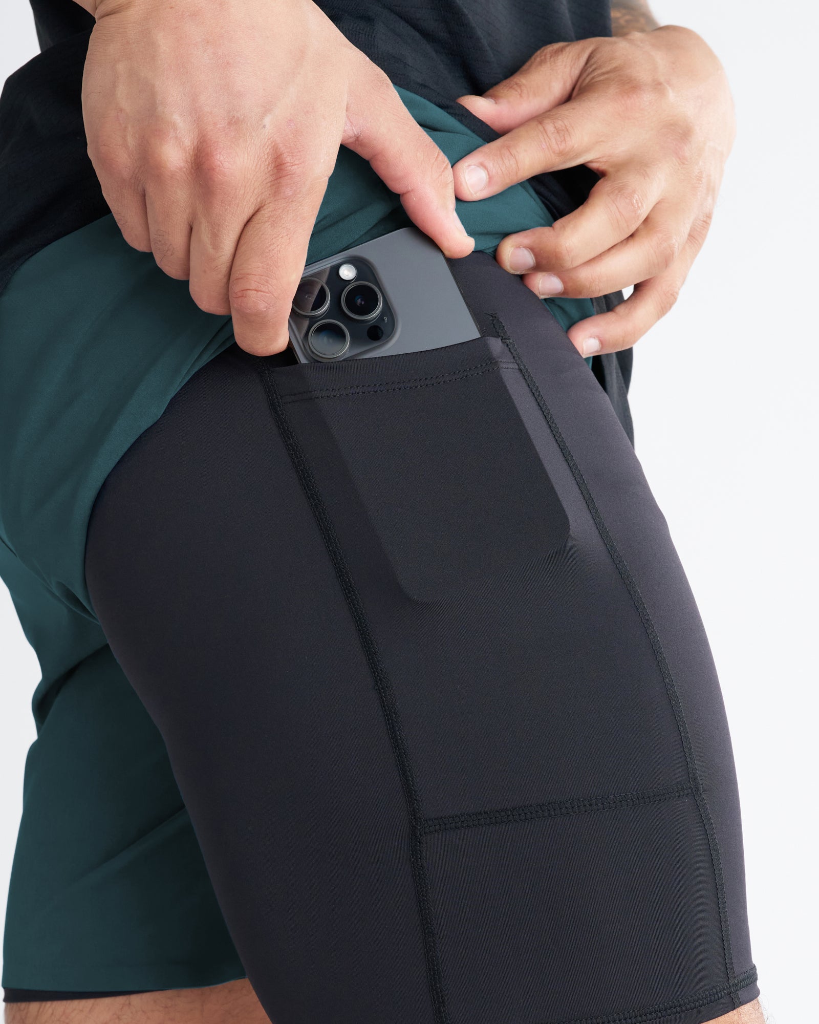 Close-up of Pulse Tech Liner Short in Teal showing a phone being inserted into the black liner's side pocket.