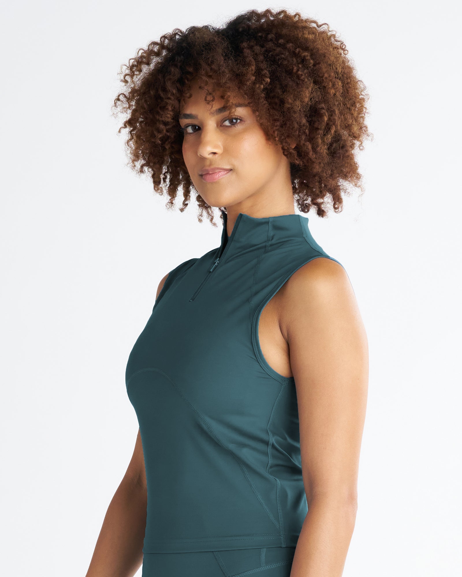 Model in a side angle view wearing the Endura-Train Quarter Zip Tank in teal, showing mock neck zipper detail.