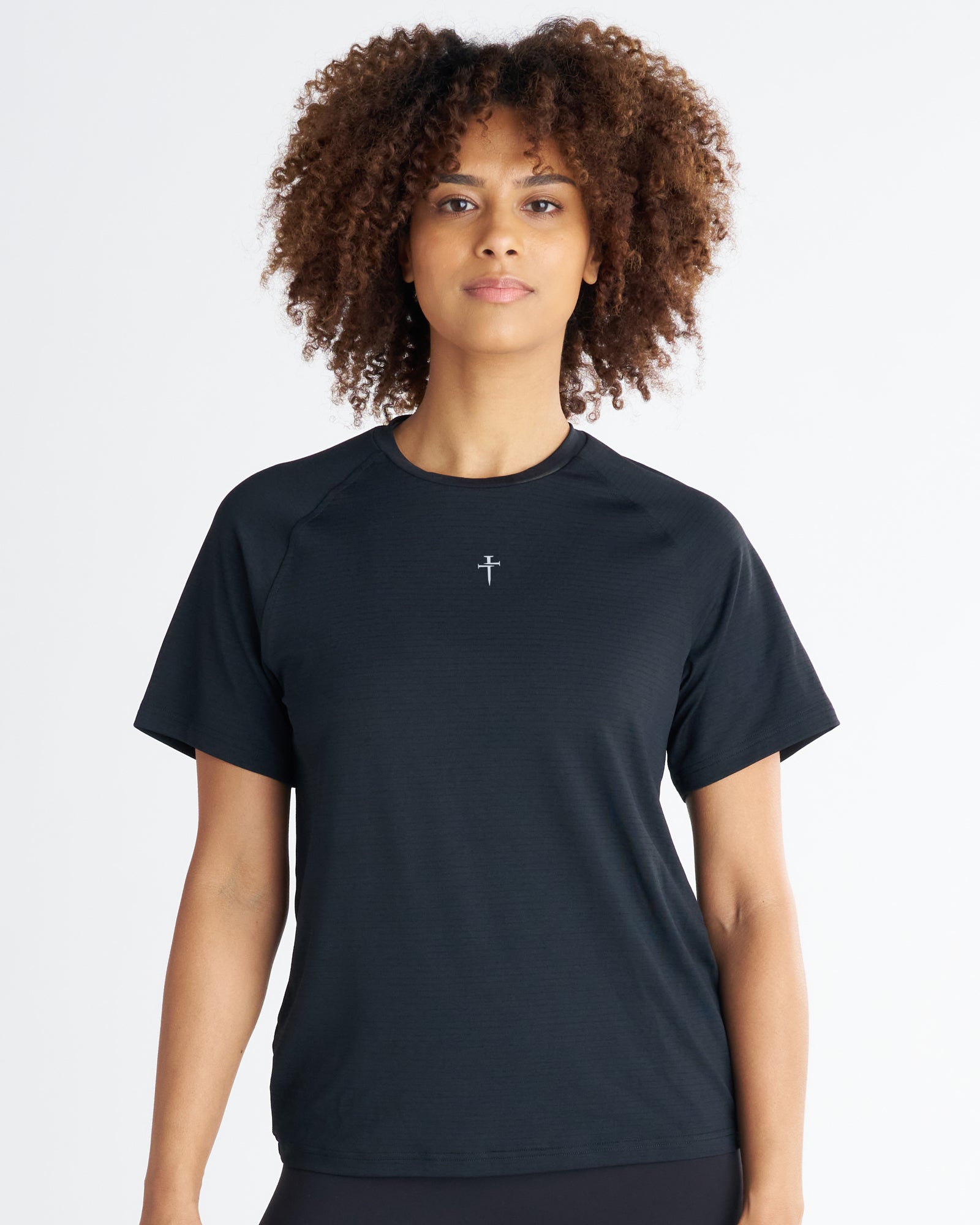 Women's Aion-Lite Tee Cross in black, front view on model, featuring a small cross logo at center chest.