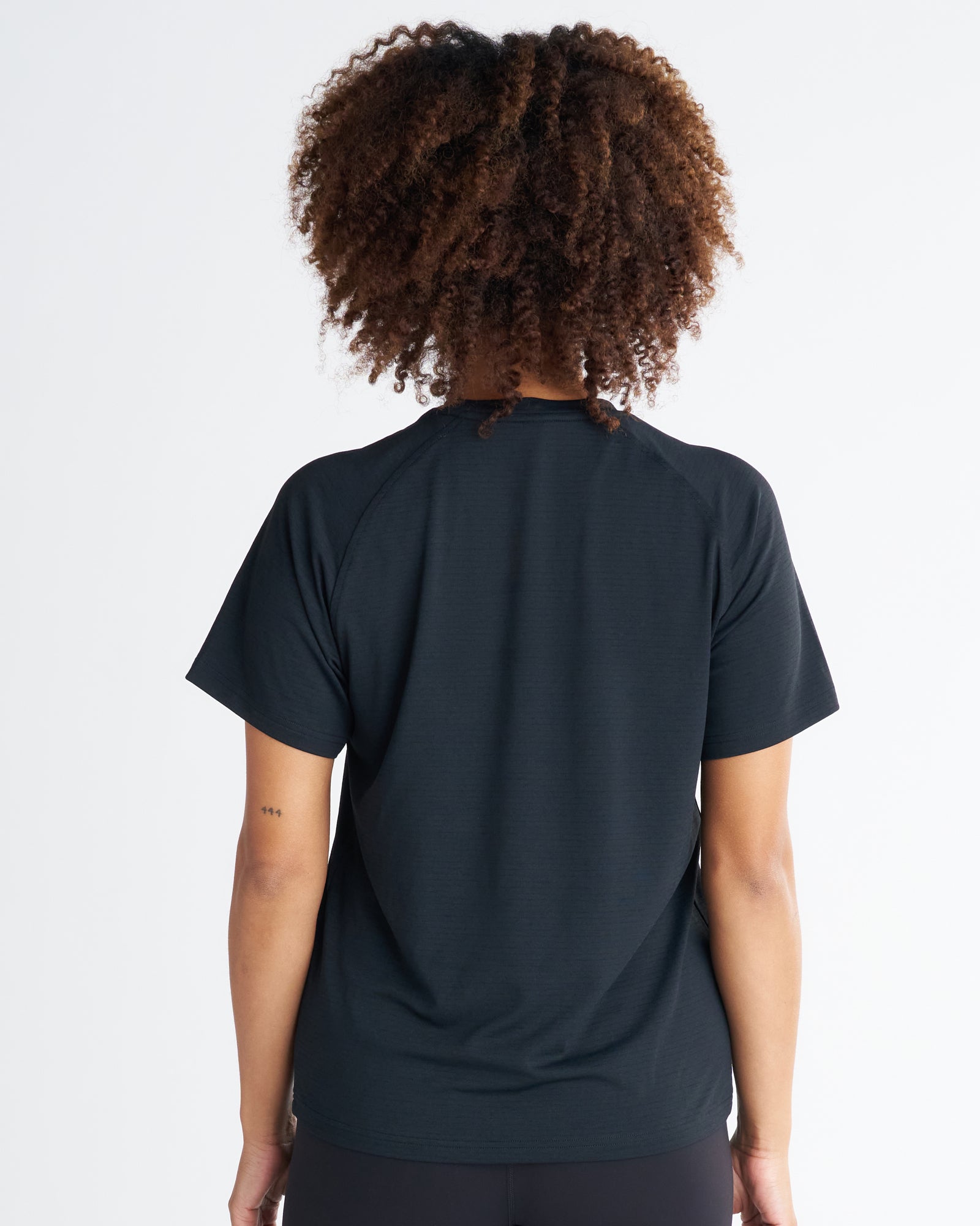 Back view of the Women's Aion-Lite Tee Cross in black, showing raglan sleeves and a relaxed fit.