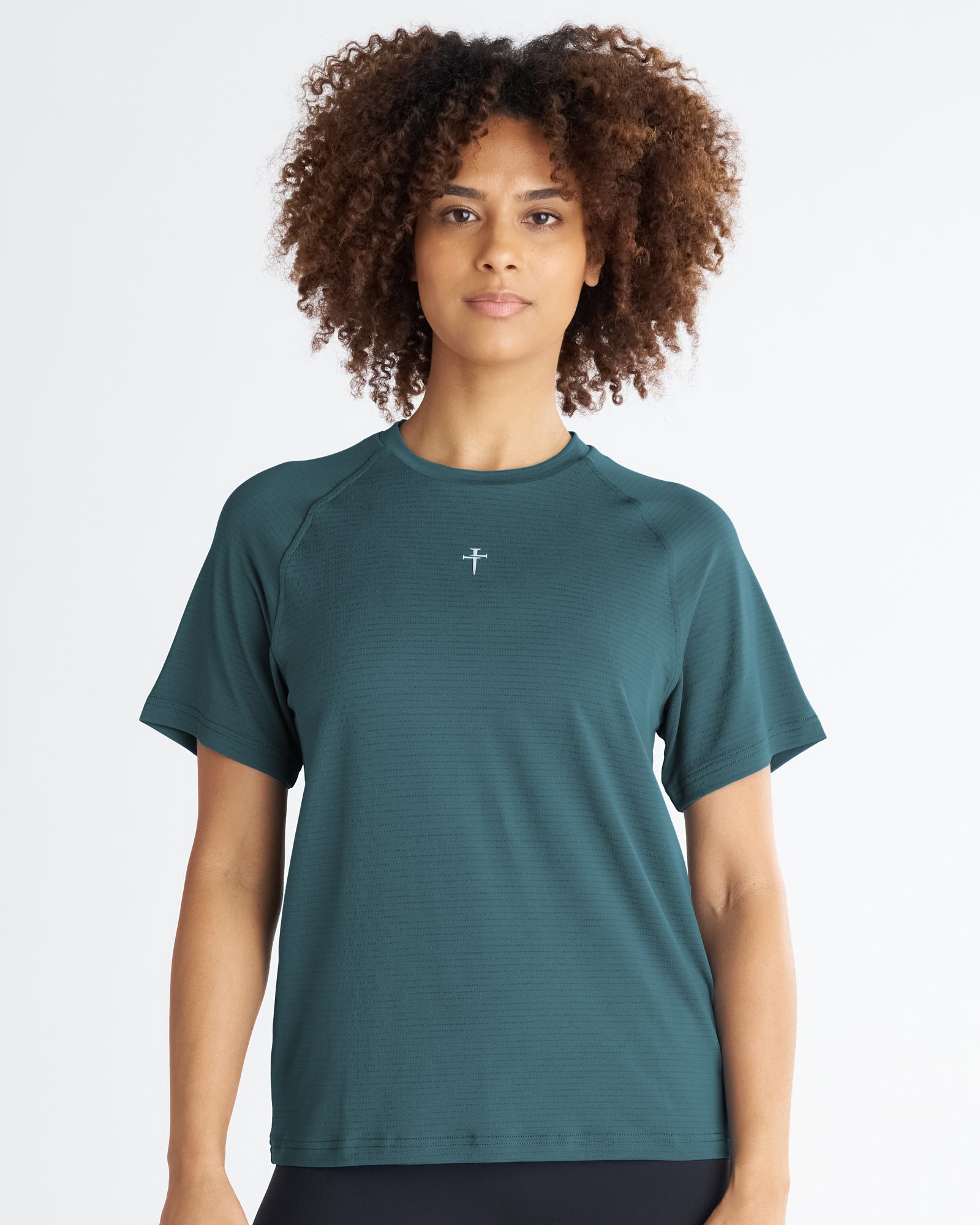 Women's Aion-Lite Tee Cross in teal, front view on model, featuring raglan sleeves and small cross logo at center chest.