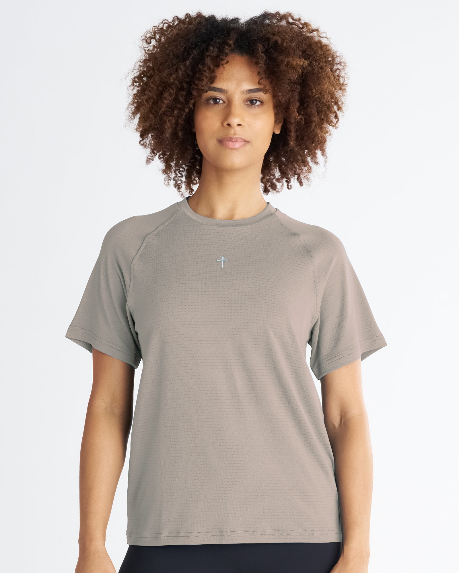 Women's Aion-Lite Tee Cross in Sand, front view on model, relaxed fit with raglan sleeves and small cross logo at chest.