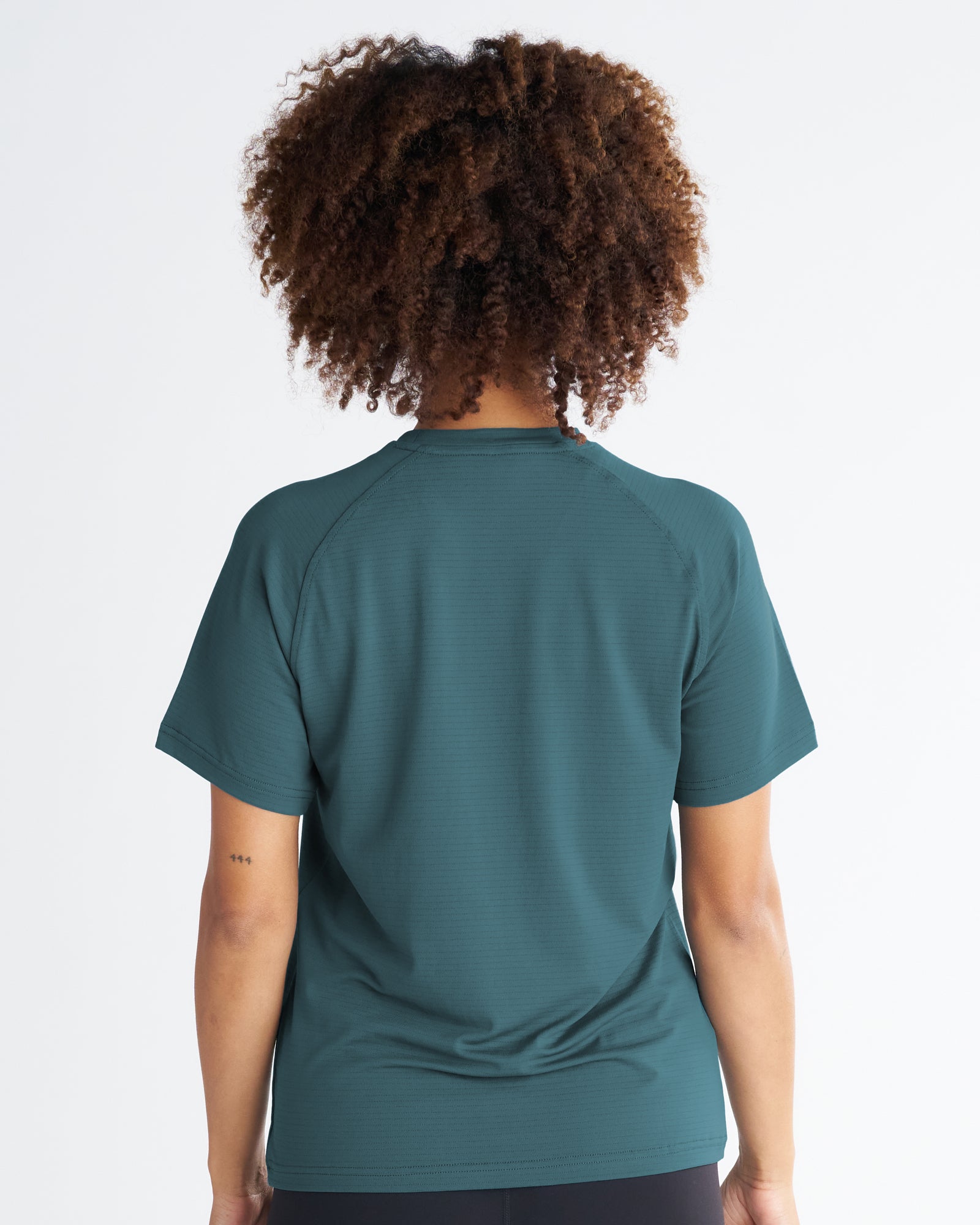 Back view of the Women's Aion-Lite Tee Cross in teal, showing raglan sleeves and subtle texture.