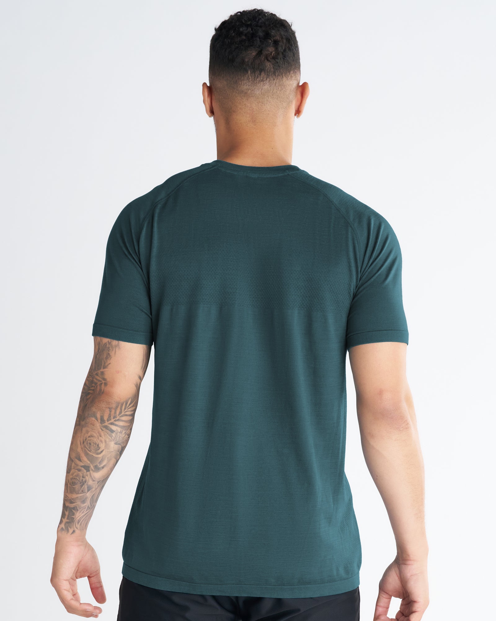 Back view of a model wearing the Seamless Tee in Teal, showing raglan sleeves and subtle texture detail.